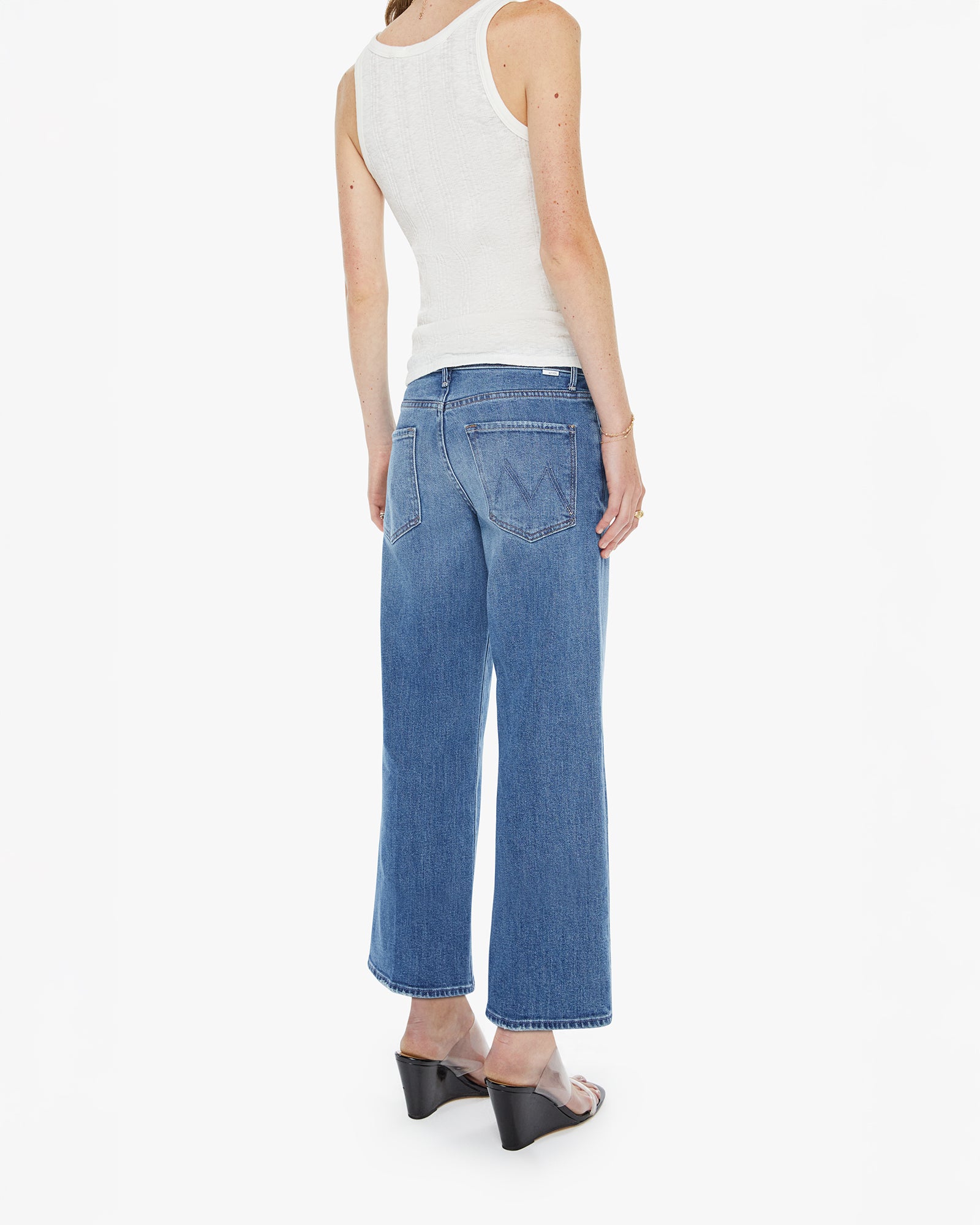 Person wearing blue jeans and a white top on a white background