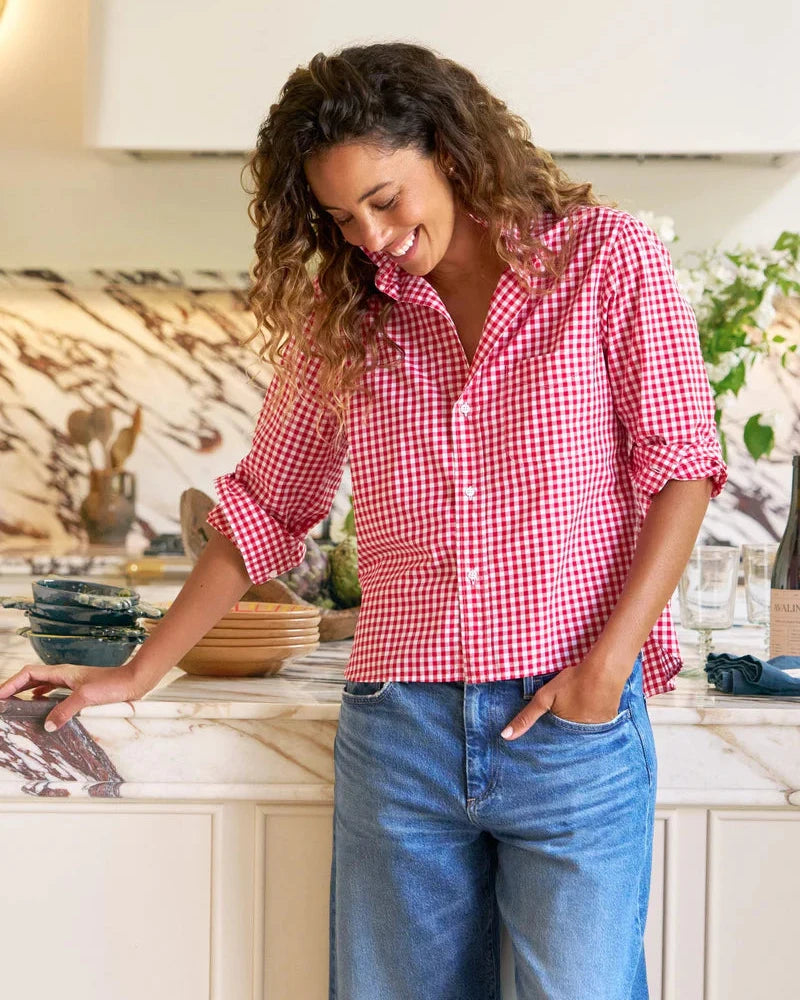 Woman in a red checkered shirt and blue jeans standing in a kitchen.