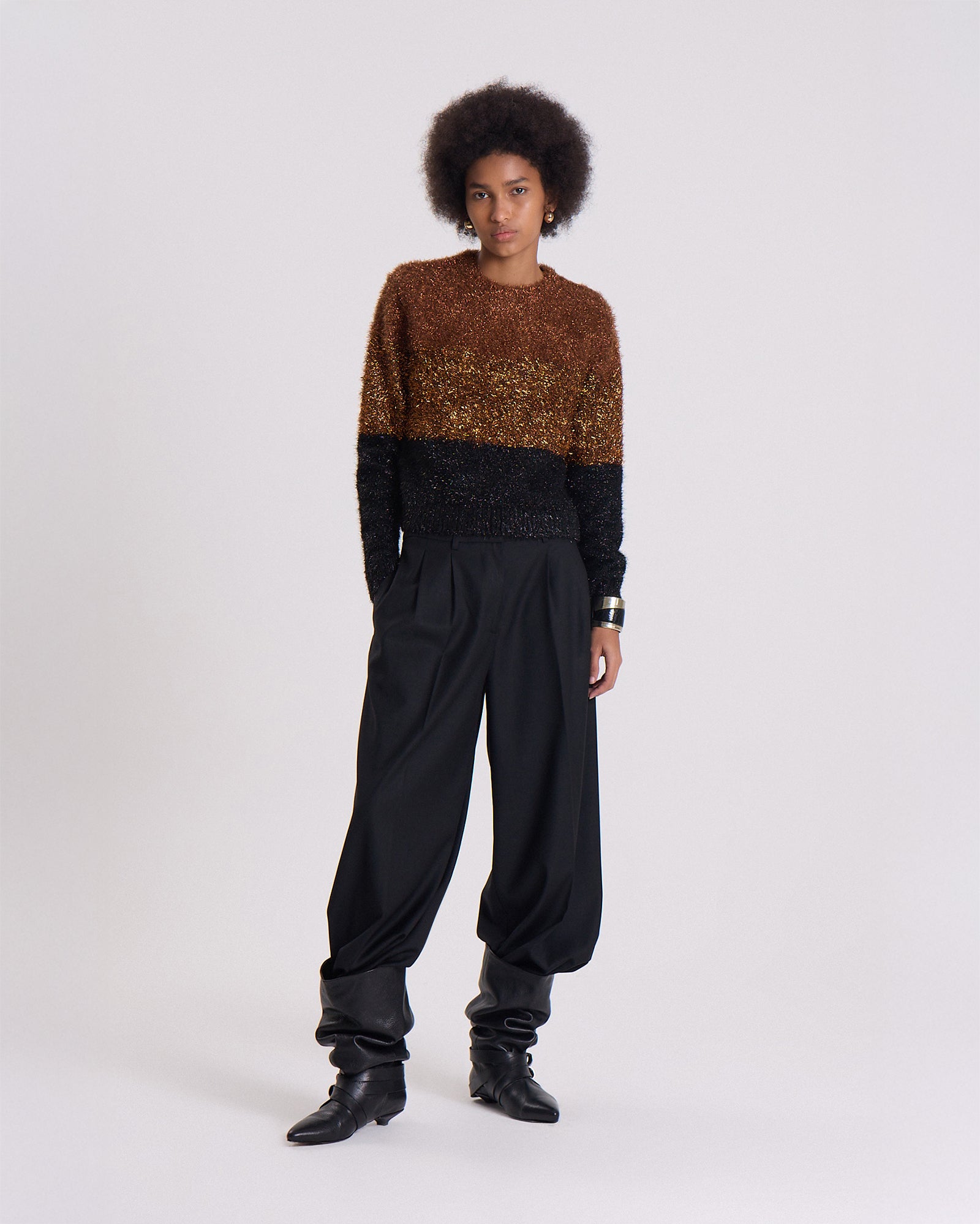 Person wearing a two-tone sweater and black pants on a white background
