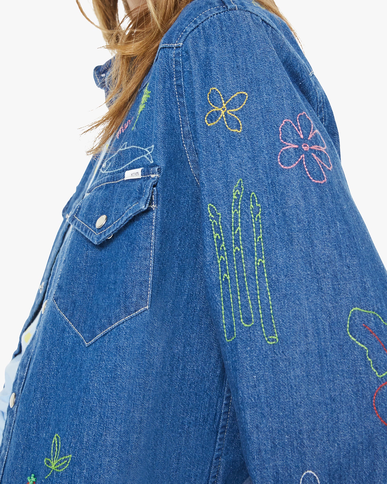 Blue denim jacket with colorful embroidery on a white background
