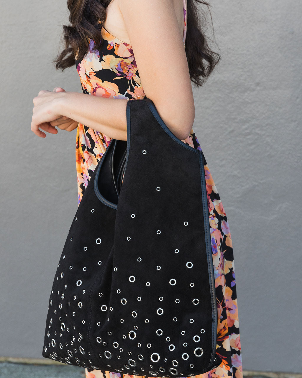Person holding a black bag with white circular patterns against a gray background