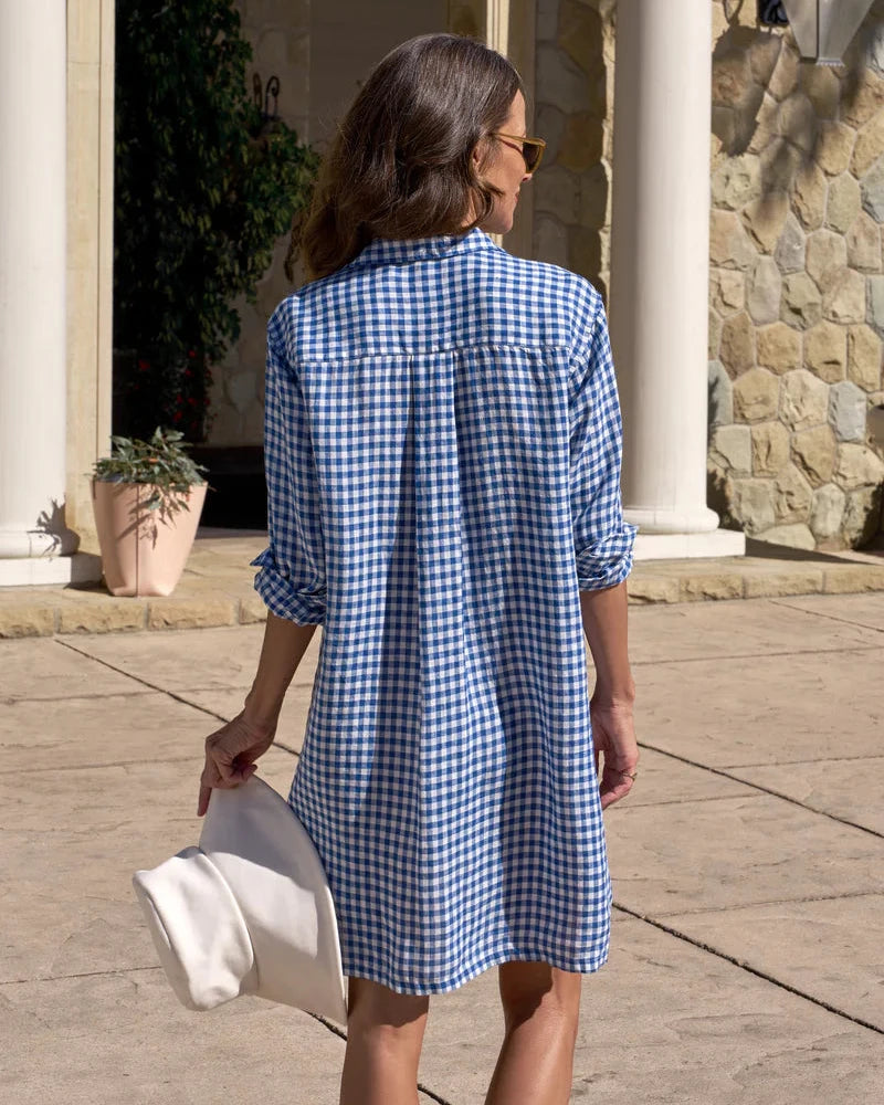 Woman wearing a blue checkered dress walking outdoors.