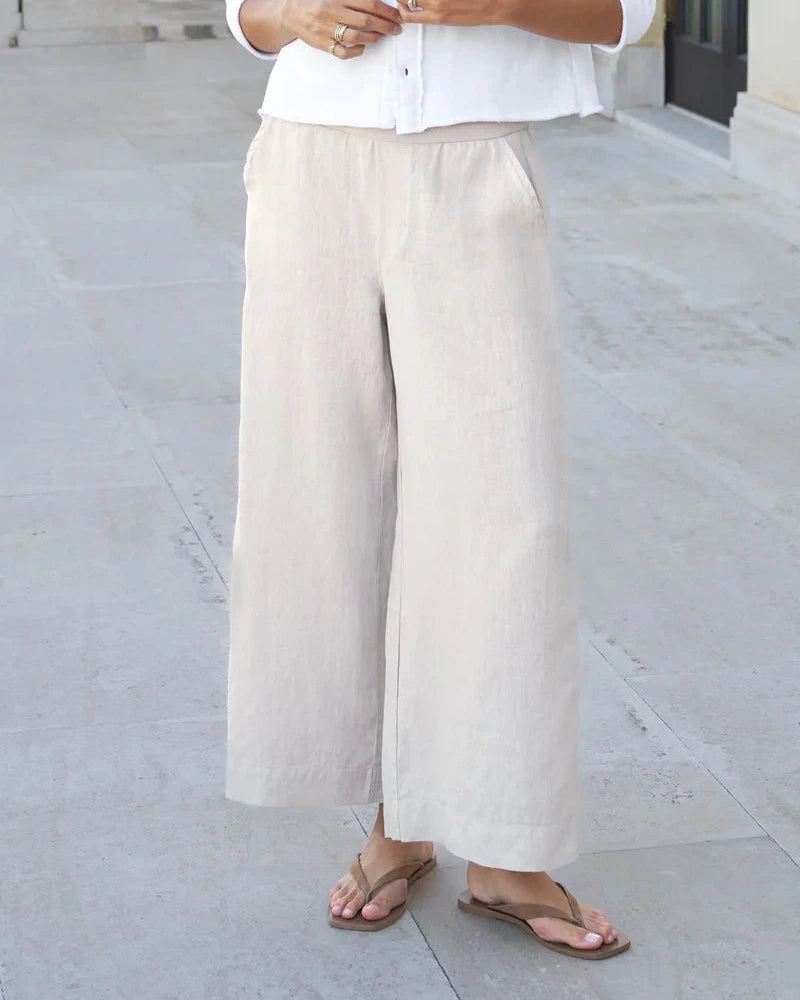 Person wearing beige wide-leg pants and a white shirt on a light gray pavement.