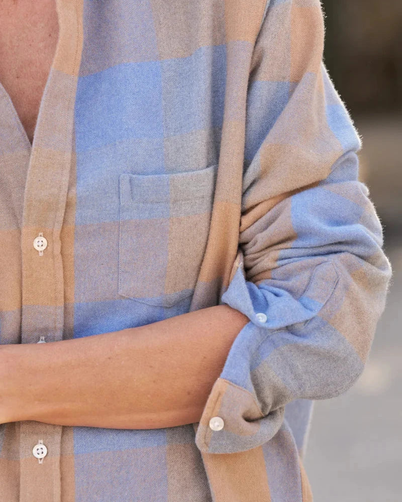 Close-up of a person wearing a plaid shirt with rolled-up sleeves.