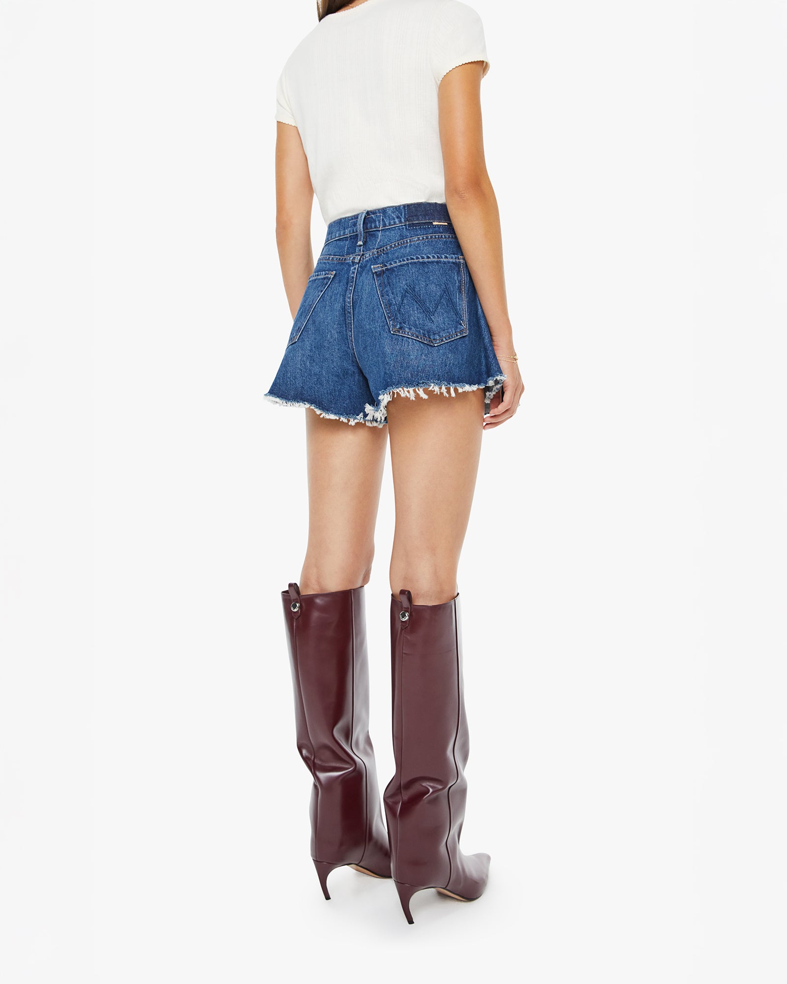 Person wearing high-waisted denim shorts and burgundy knee-high boots on a white background