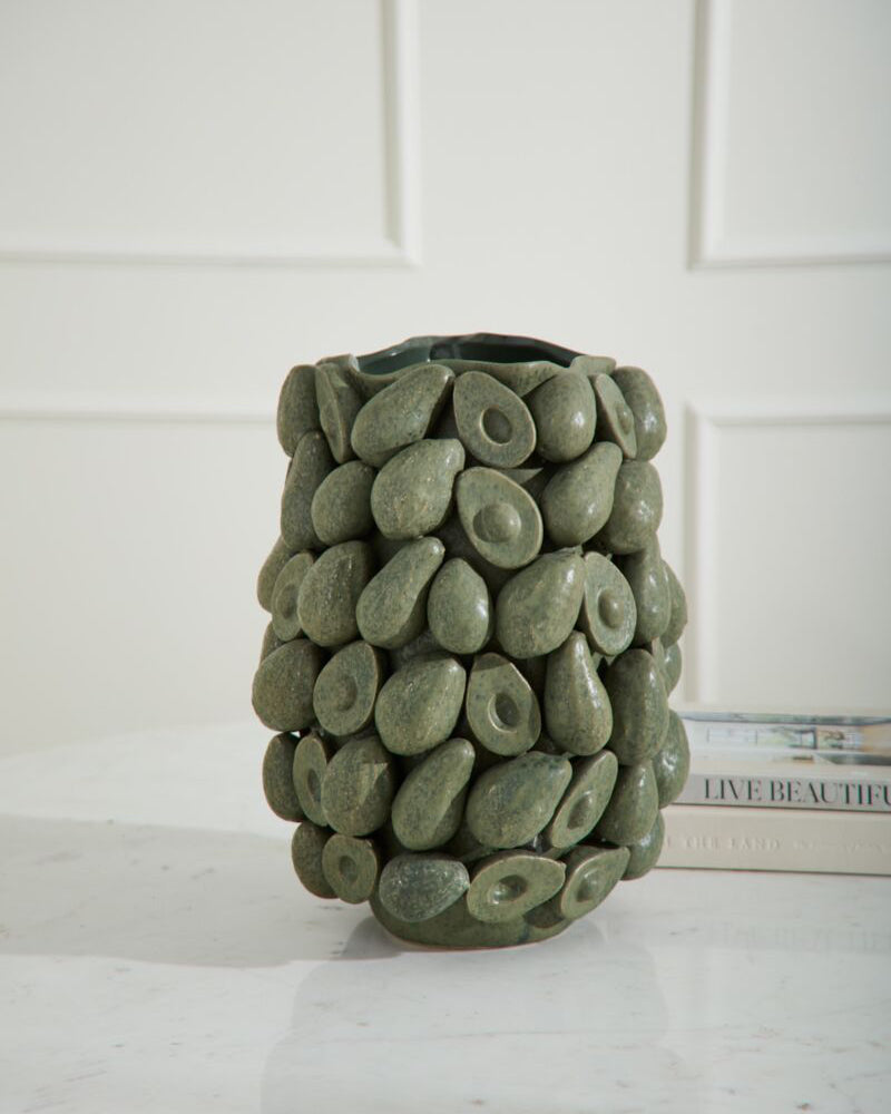 Green stone-textured vase on a white surface with a white paneled wall background