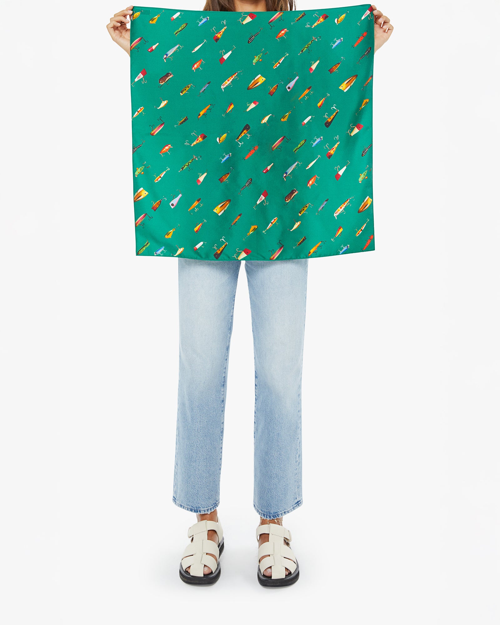 Person holding a green scarf with colorful patterns on a white background