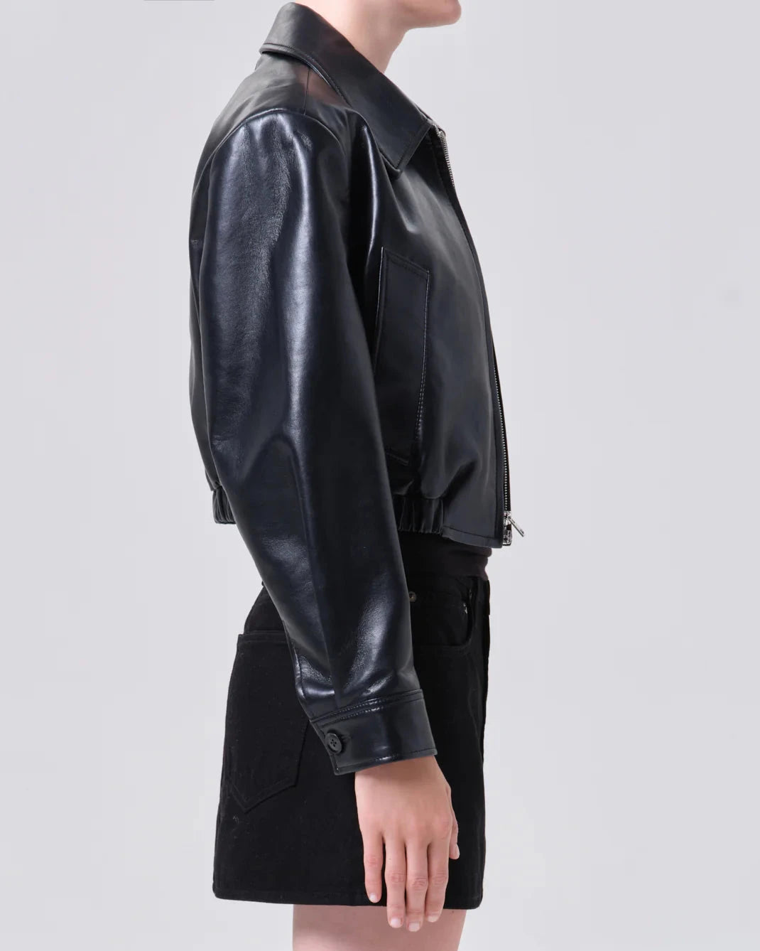 Person wearing a black leather jacket on a light gray background
