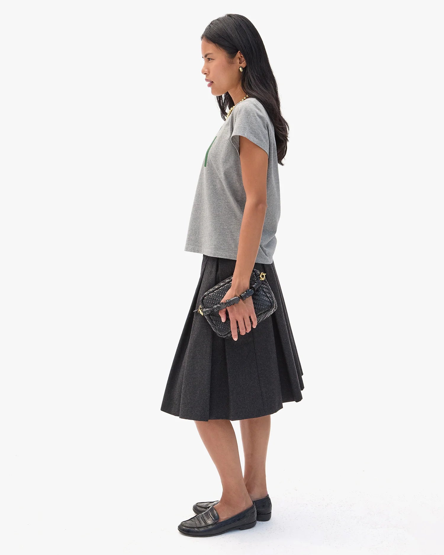 Woman wearing a gray top and black skirt with a white background