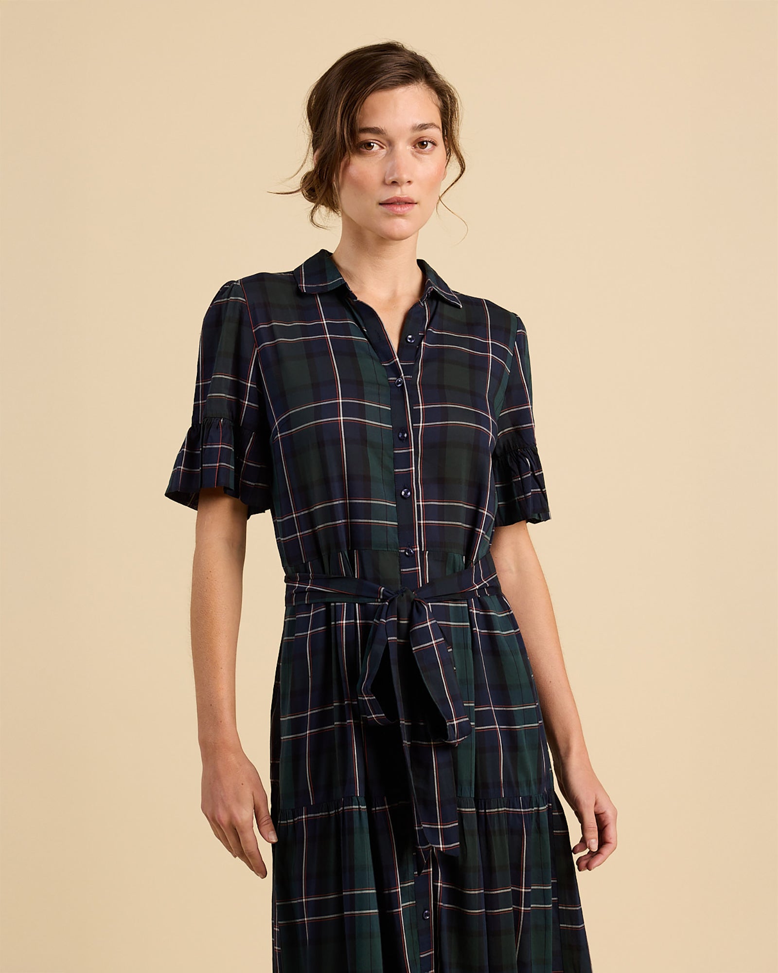 Woman wearing a plaid dress against a beige background