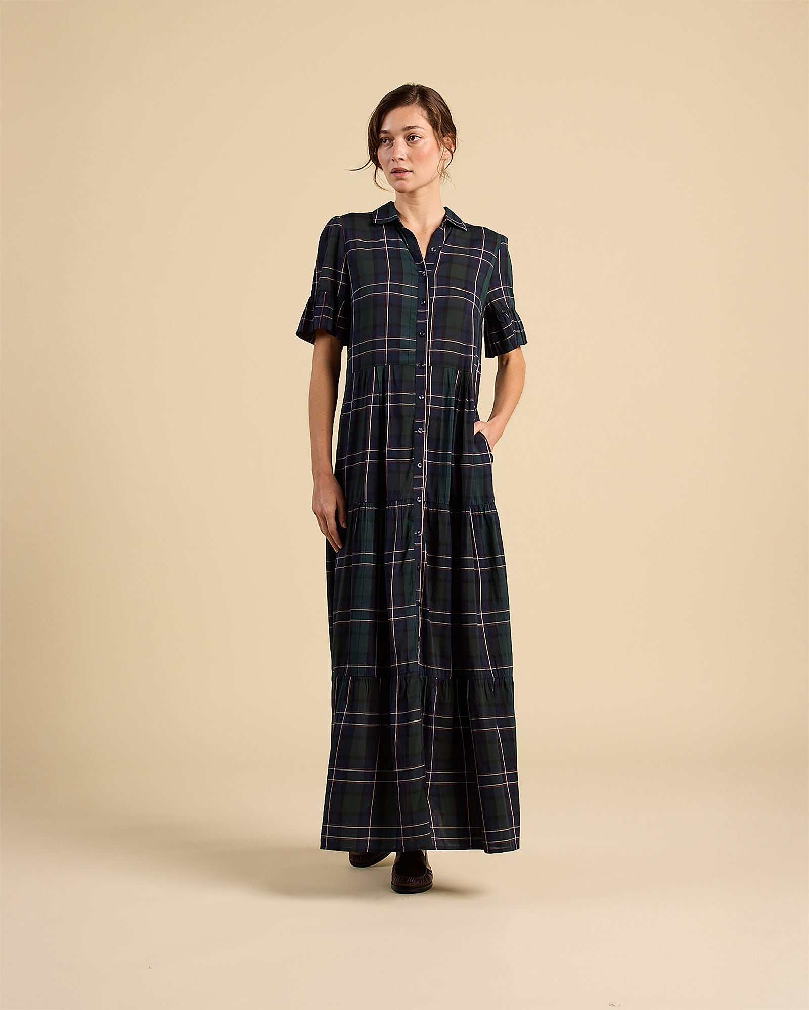 Woman wearing a long black and white checkered dress on a beige background