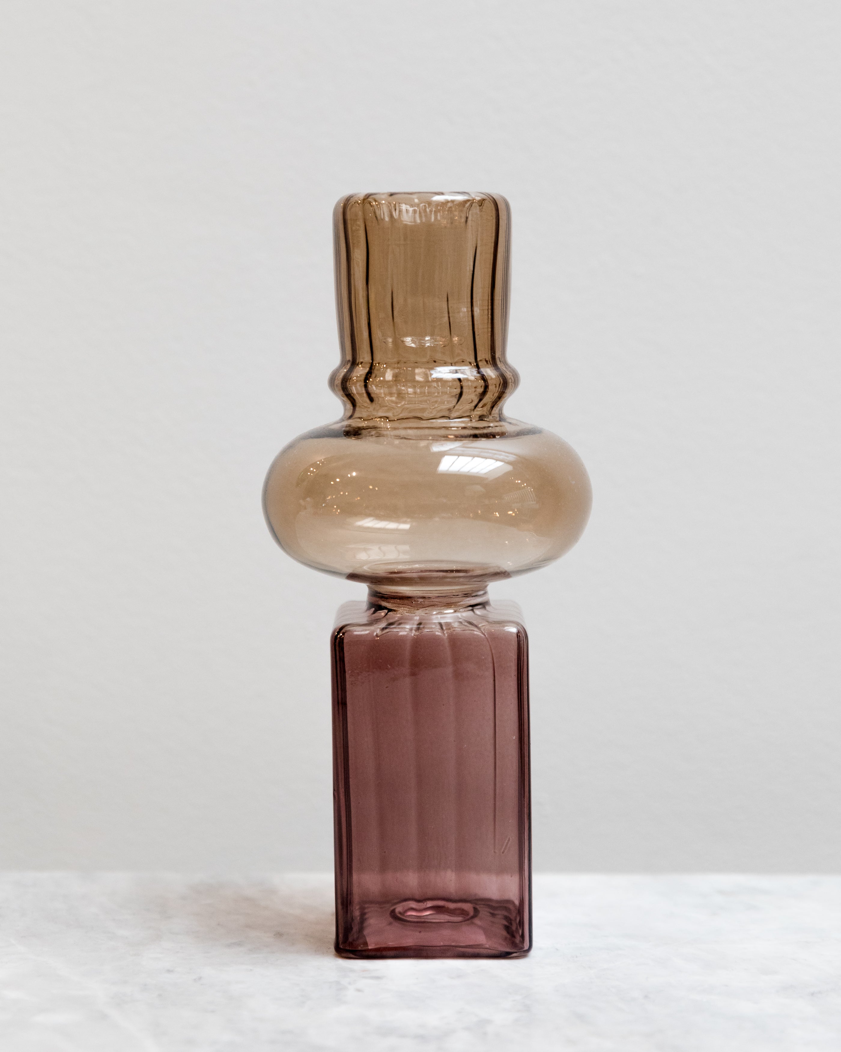 Glass bottle with a gradient from brown to purple on a white background