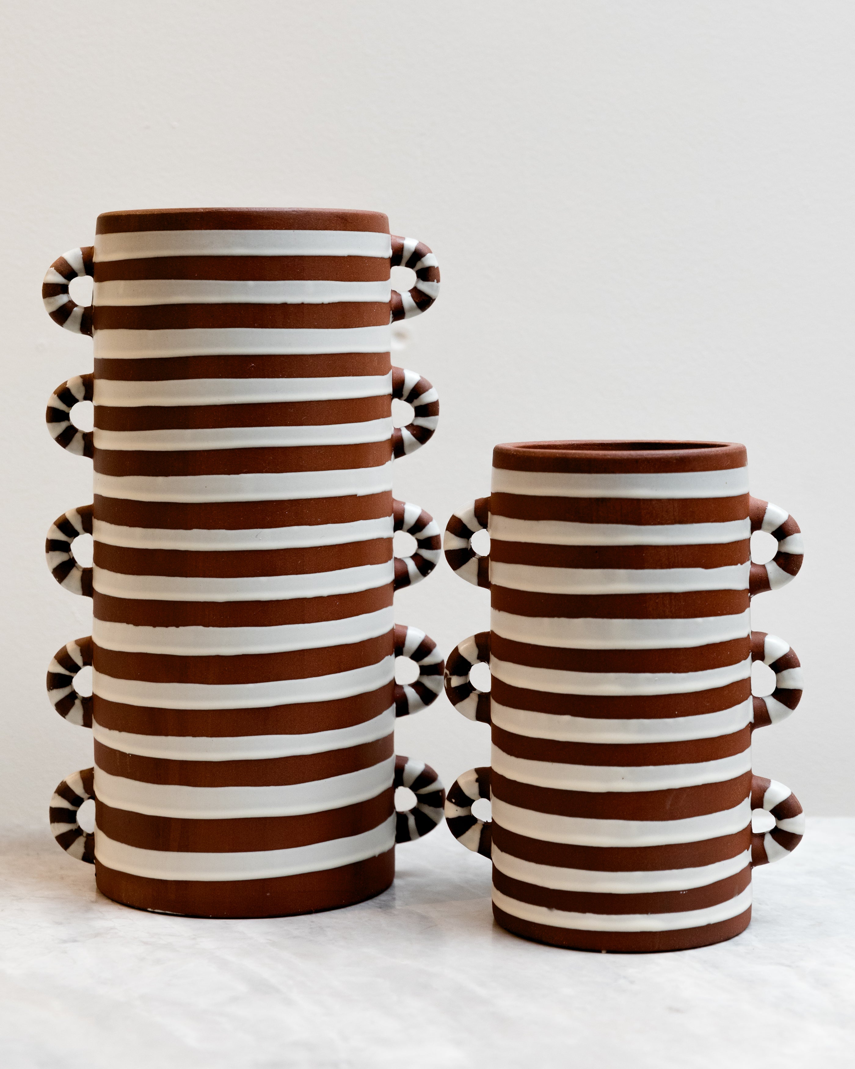 Two striped ceramic vases with decorative handles on a white background