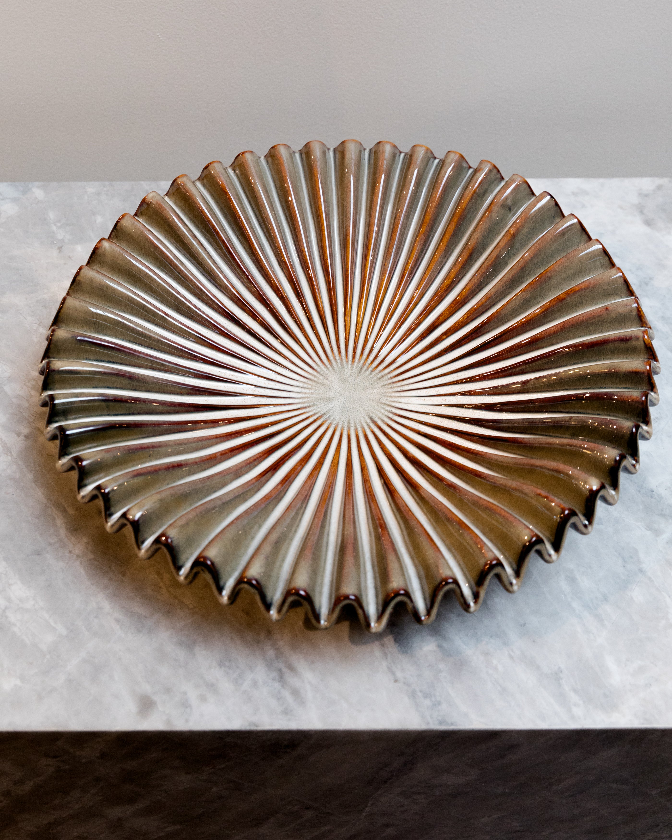Decorative metal dish with sunburst pattern on a marble surface