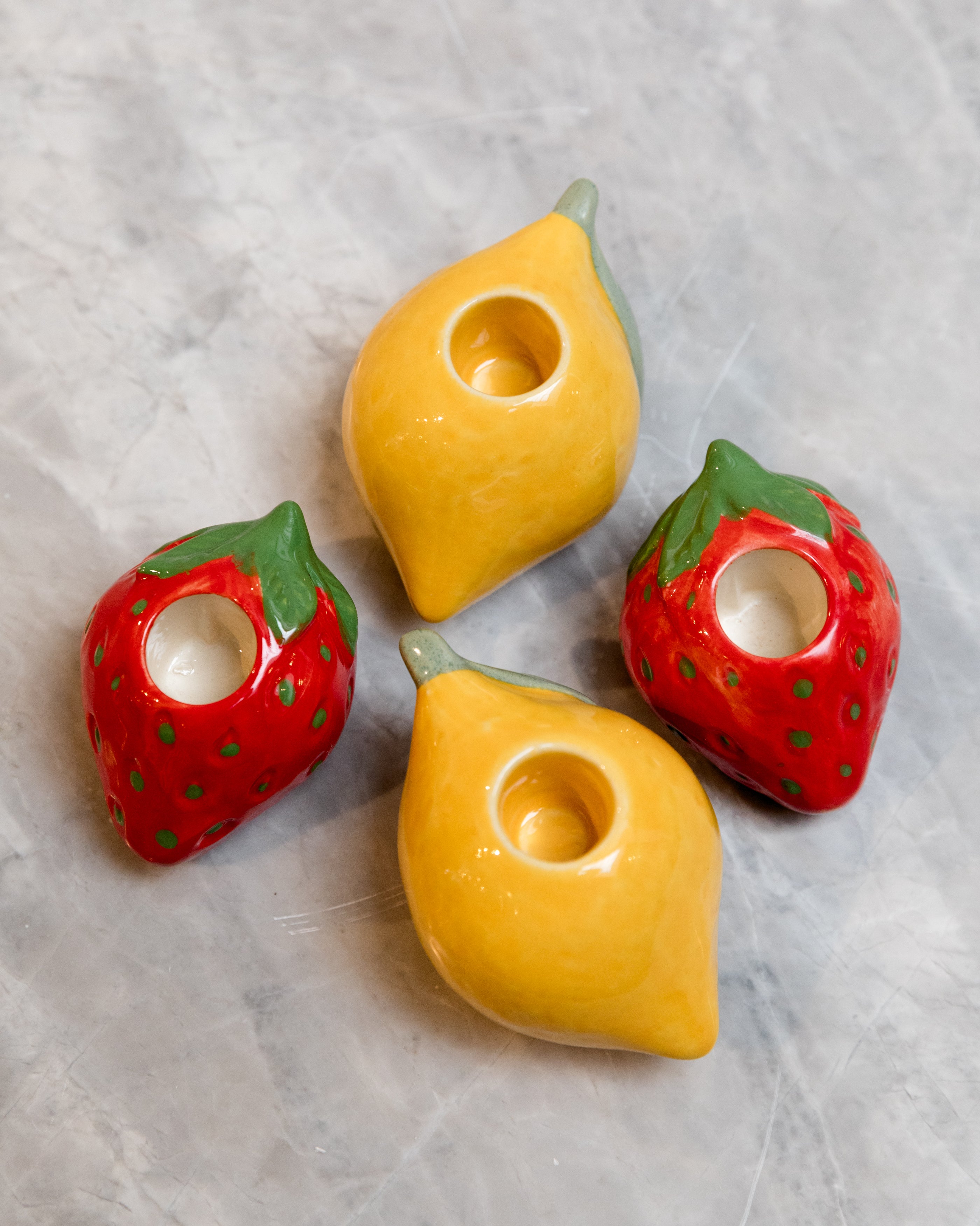 Four ceramic fruit-shaped candle holders on a textured surface