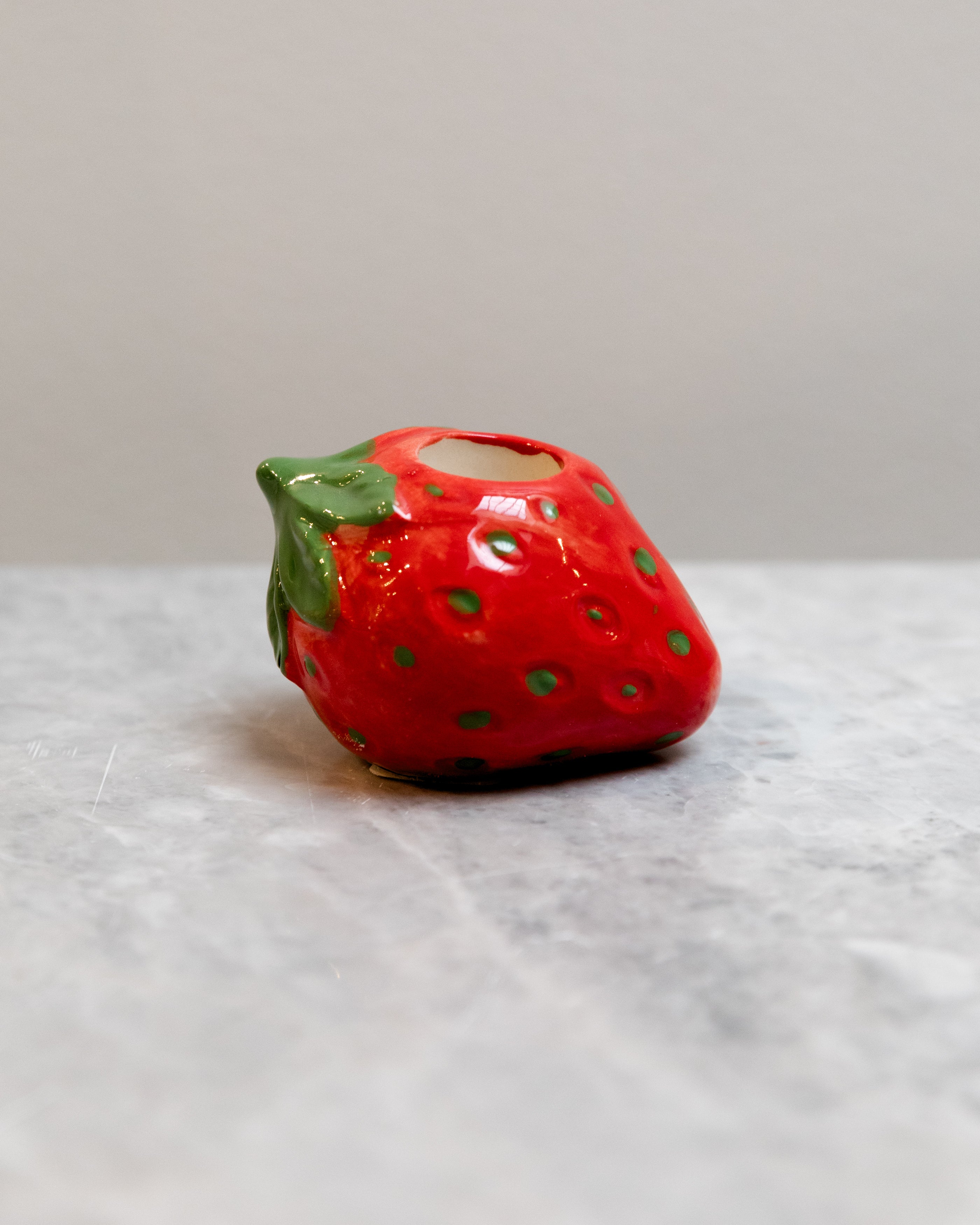 Ceramic strawberry-shaped container on a marble surface