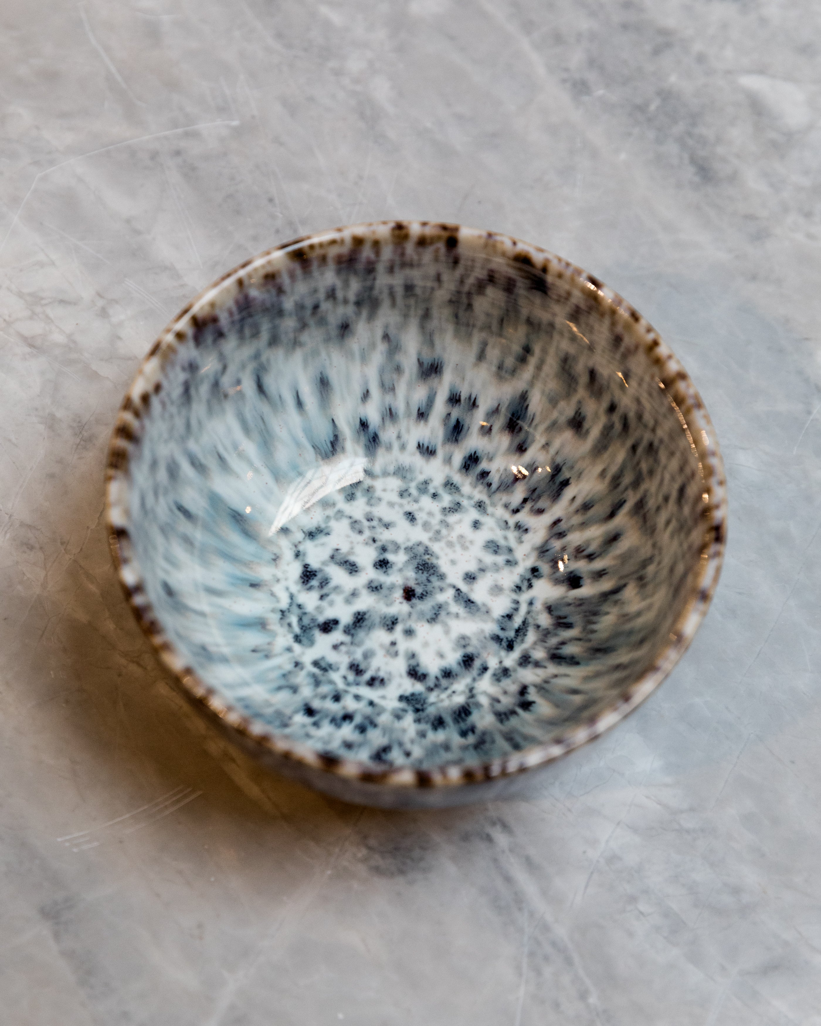 Speckled ceramic bowl on a textured gray surface