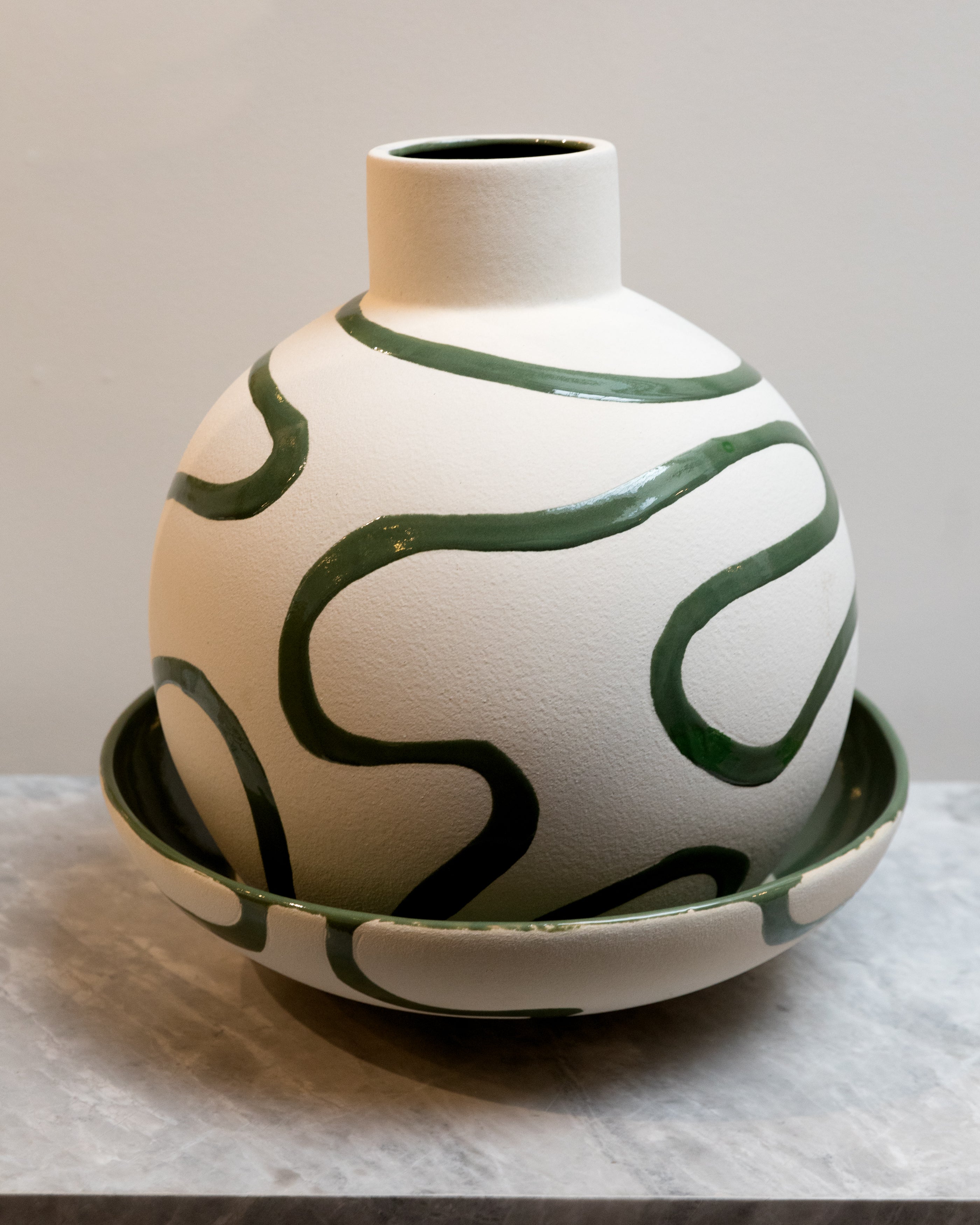 Ceramic vase with green abstract patterns on a neutral background