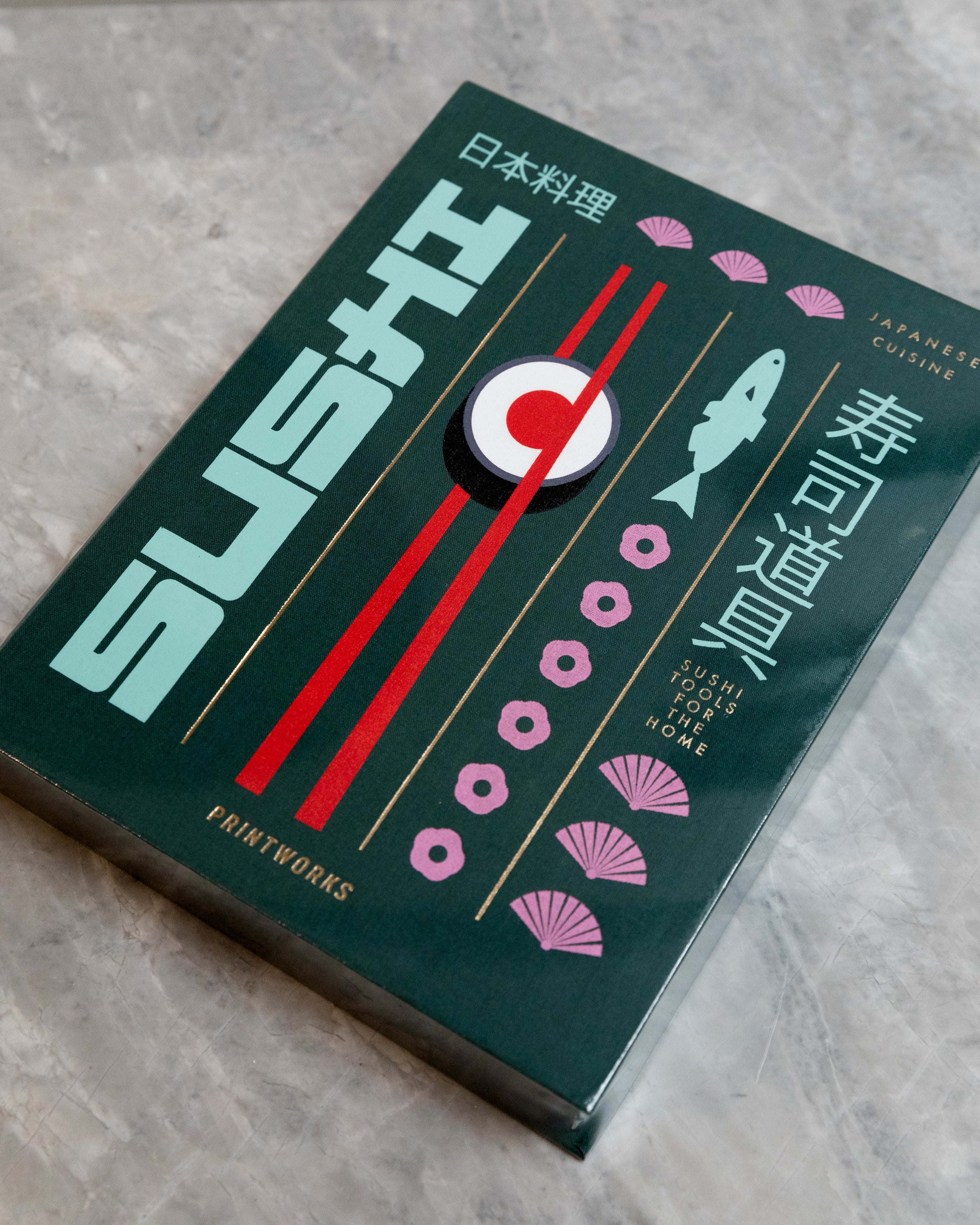 Dark green box with sushi, red chopsticks and a fish printed on the outside