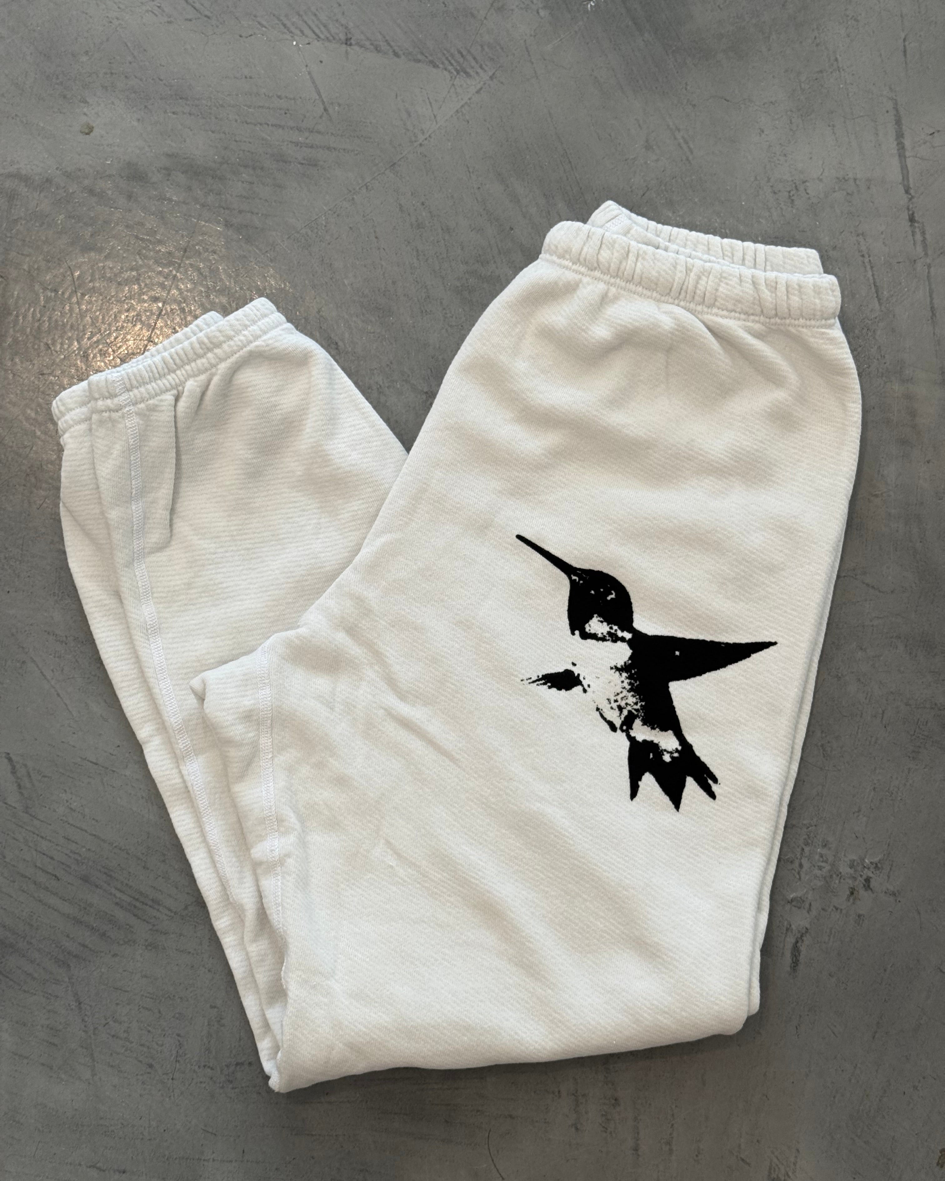 White sweatpants with a black bird design on a gray surface