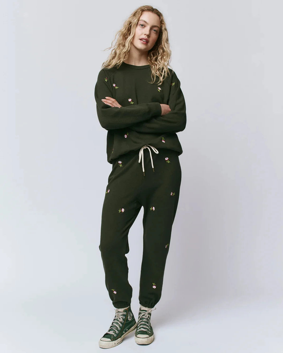 Person wearing a green tracksuit with small decorative elements on a white background