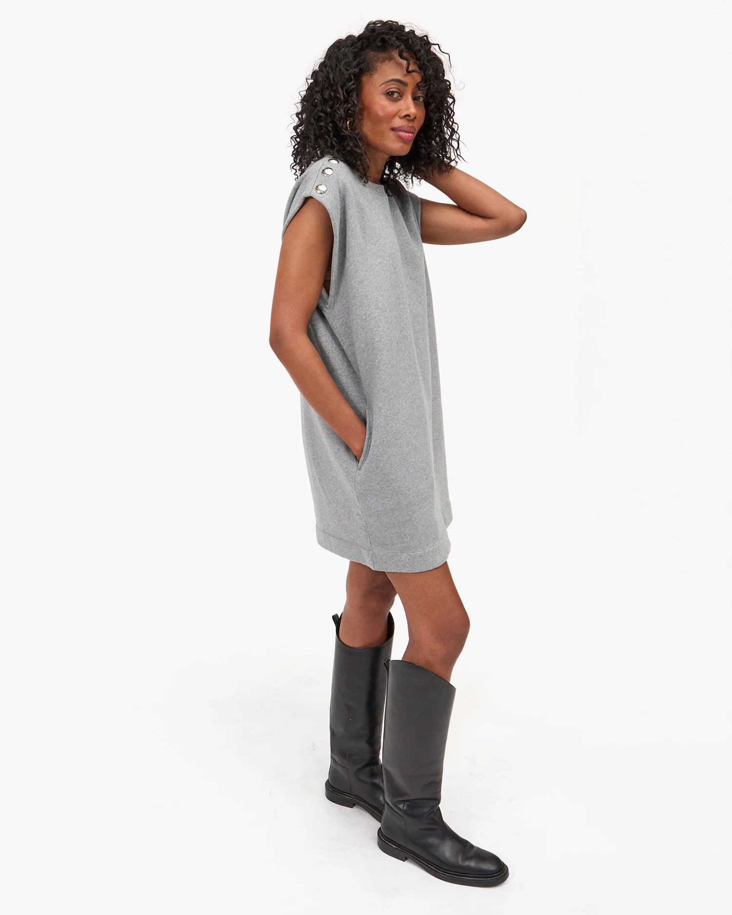 Woman wearing a gray dress and black boots on a white background