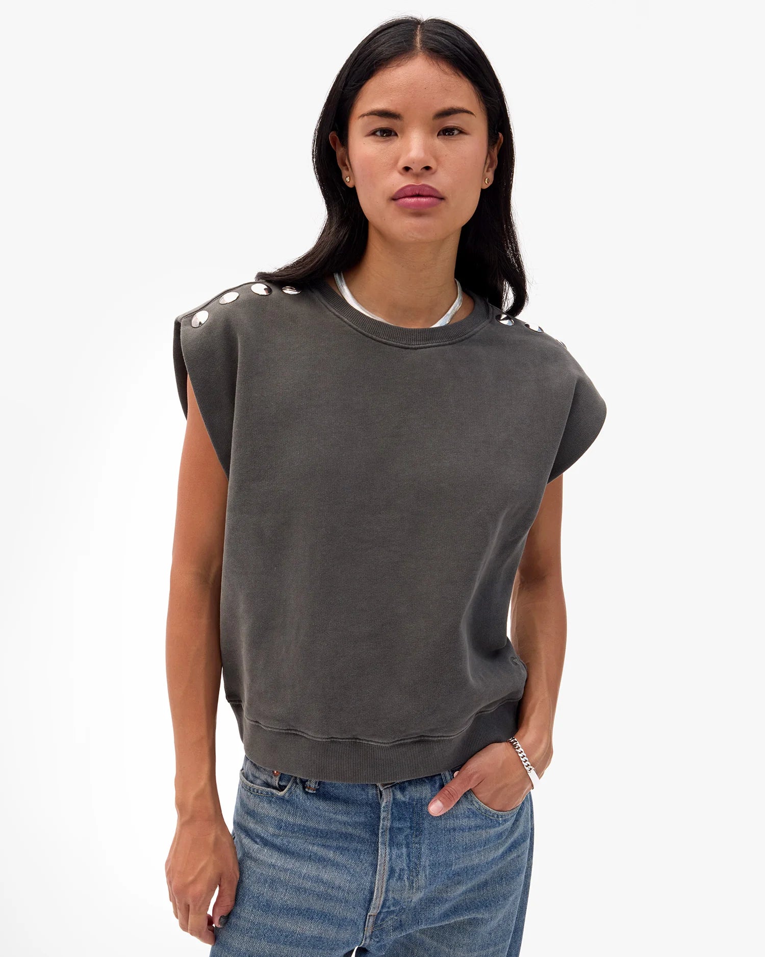 Woman wearing a dark gray sweatshirt with shoulder embellishments on a white background