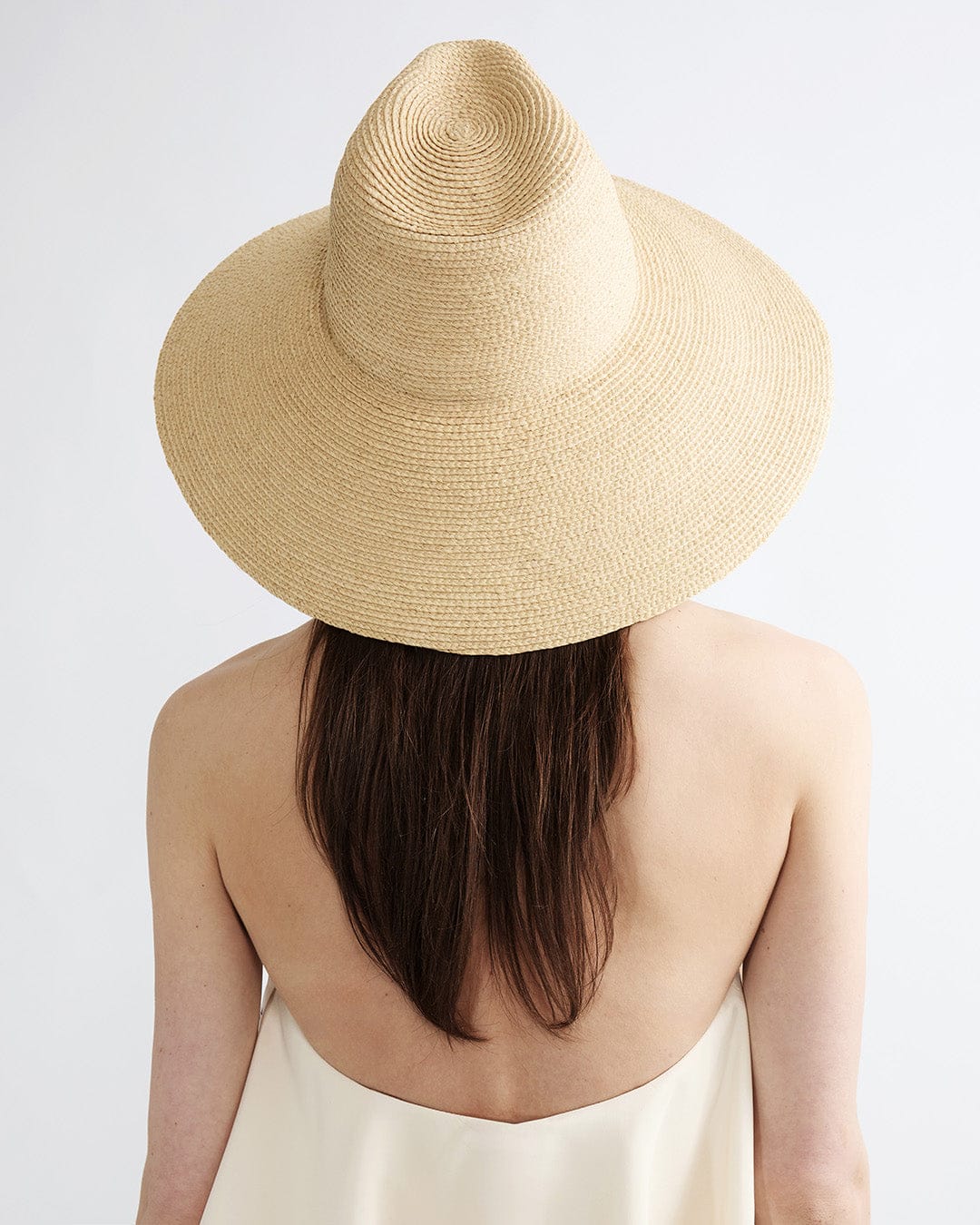 Beige straw hat worn by a person on a light gray background