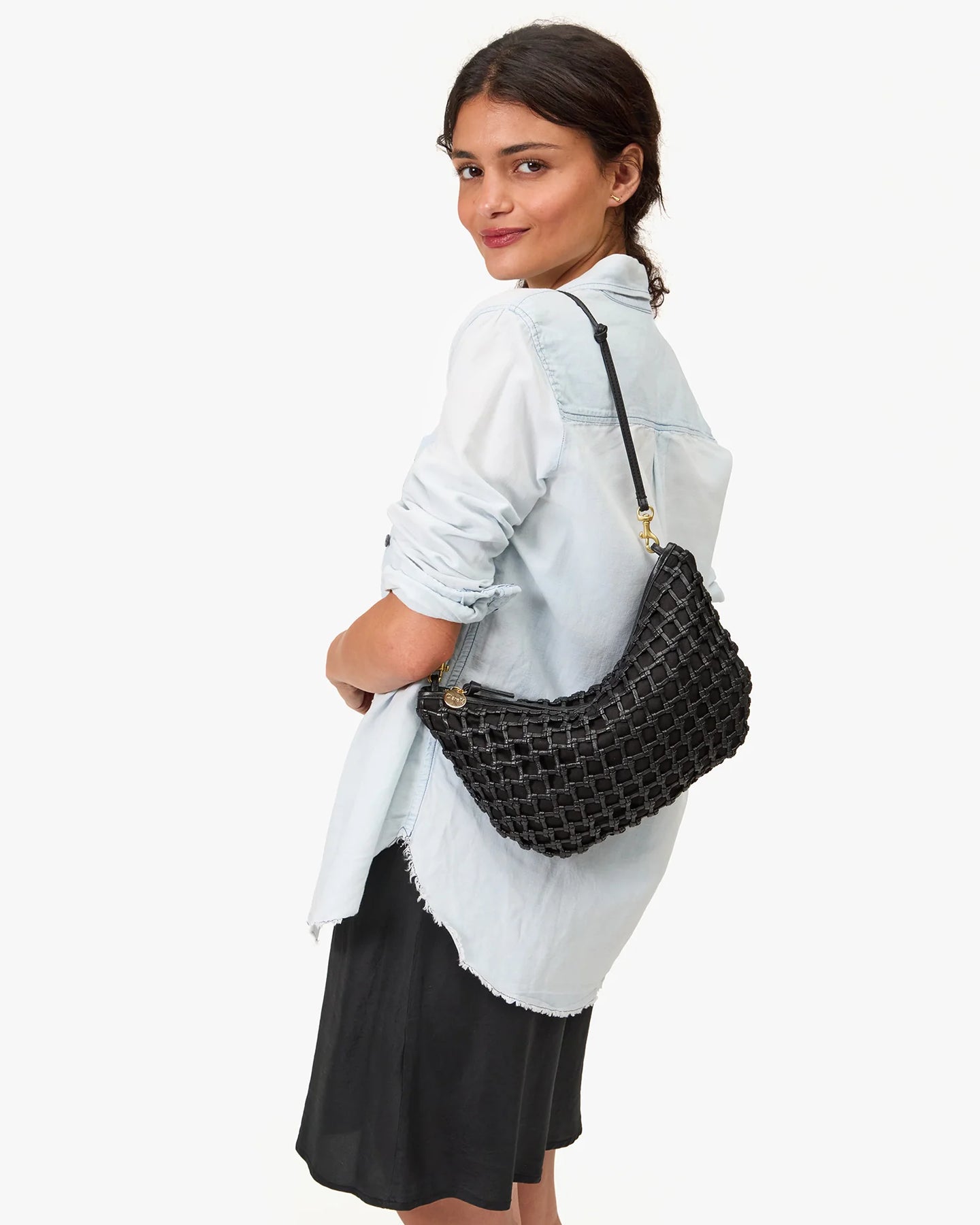Woman holding a black woven handbag against a white background
