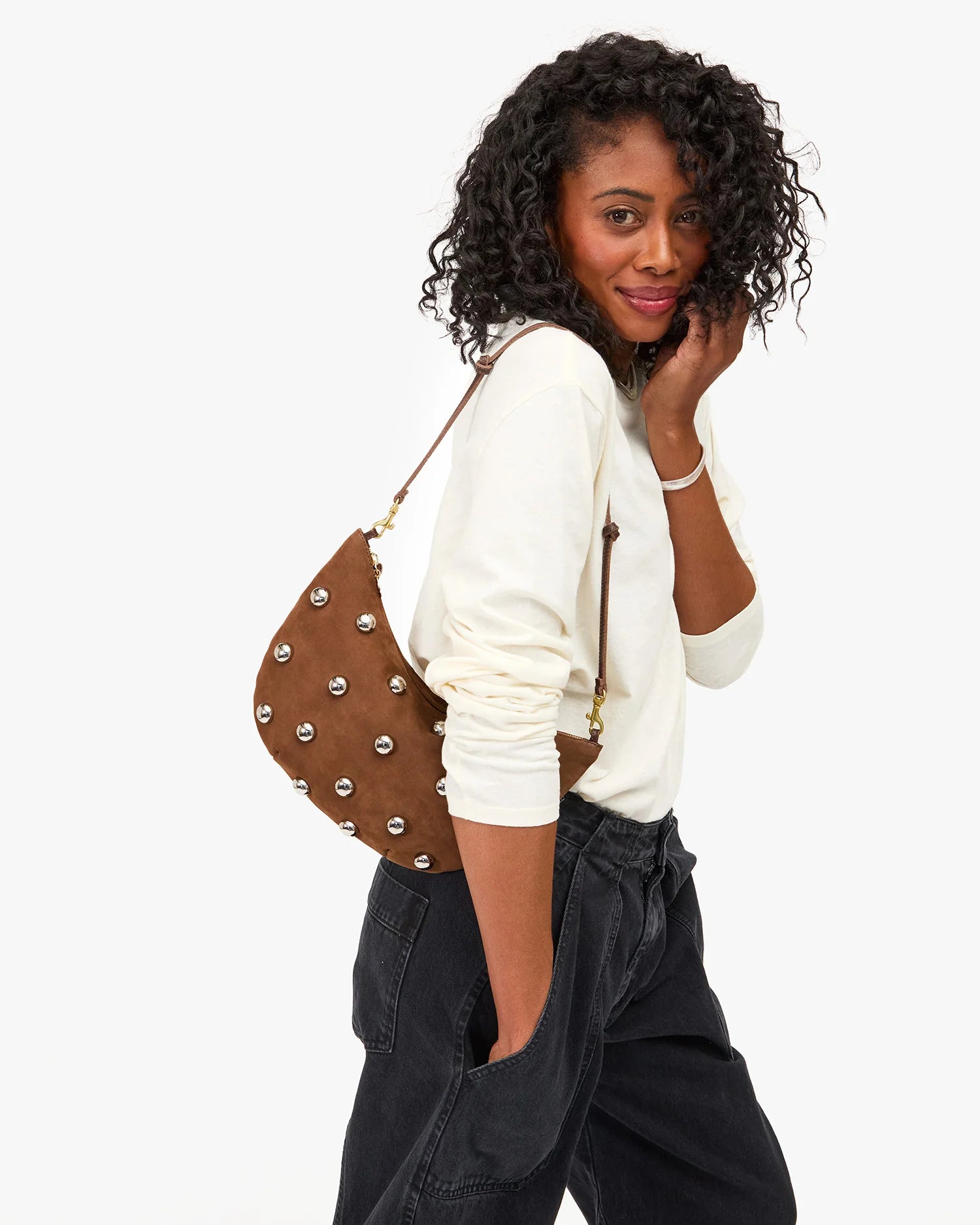 Woman holding a brown leather handbag with silver studs on a white background