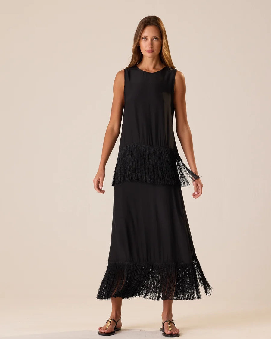 Woman wearing a black sleeveless dress with a layered skirt on a beige background