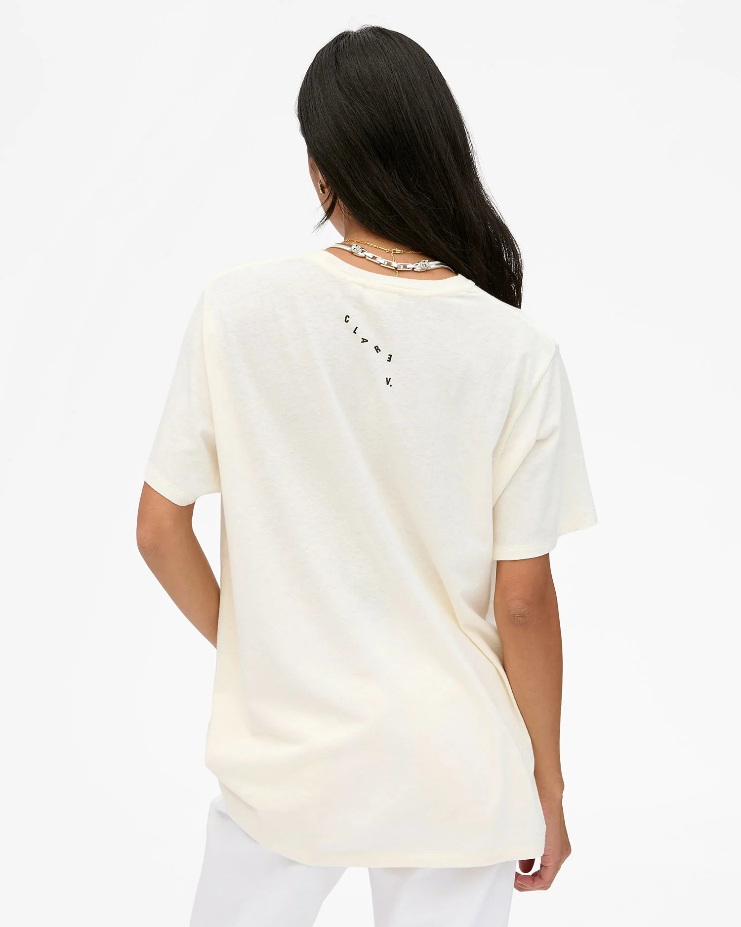 Woman wearing a cream-colored t-shirt with text on the back against a white background