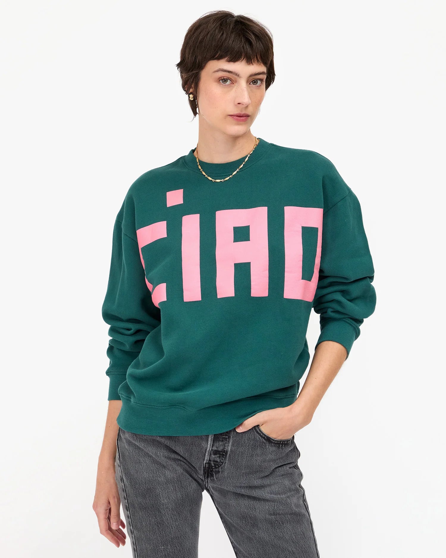 Person wearing a green sweatshirt with pink text on a white background