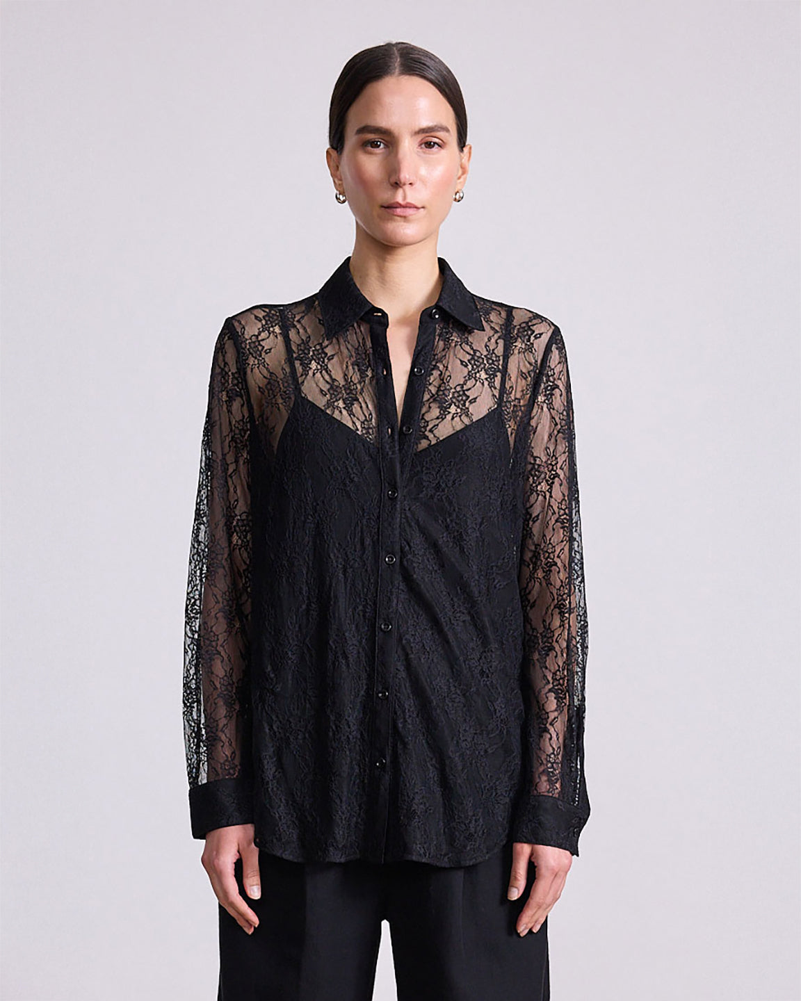 Woman wearing a black lace-trimmed shirt against a plain background