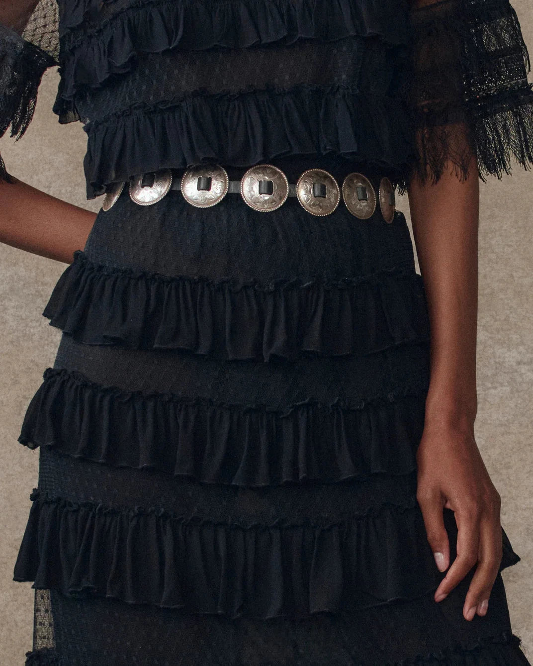 Black ruffled skirt and top with silver buttons on a neutral background