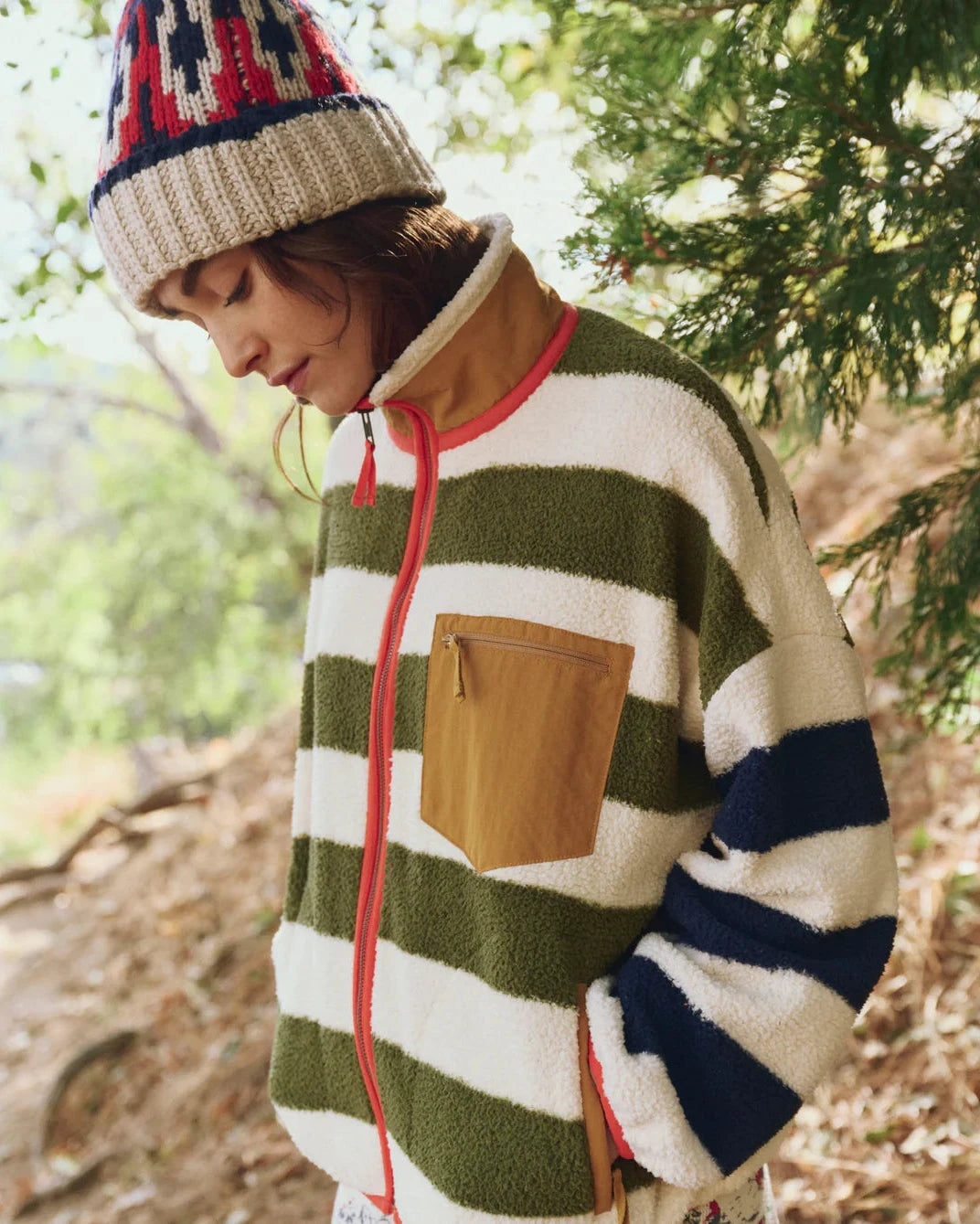 Person wearing a striped sweater and beanie in a forest setting