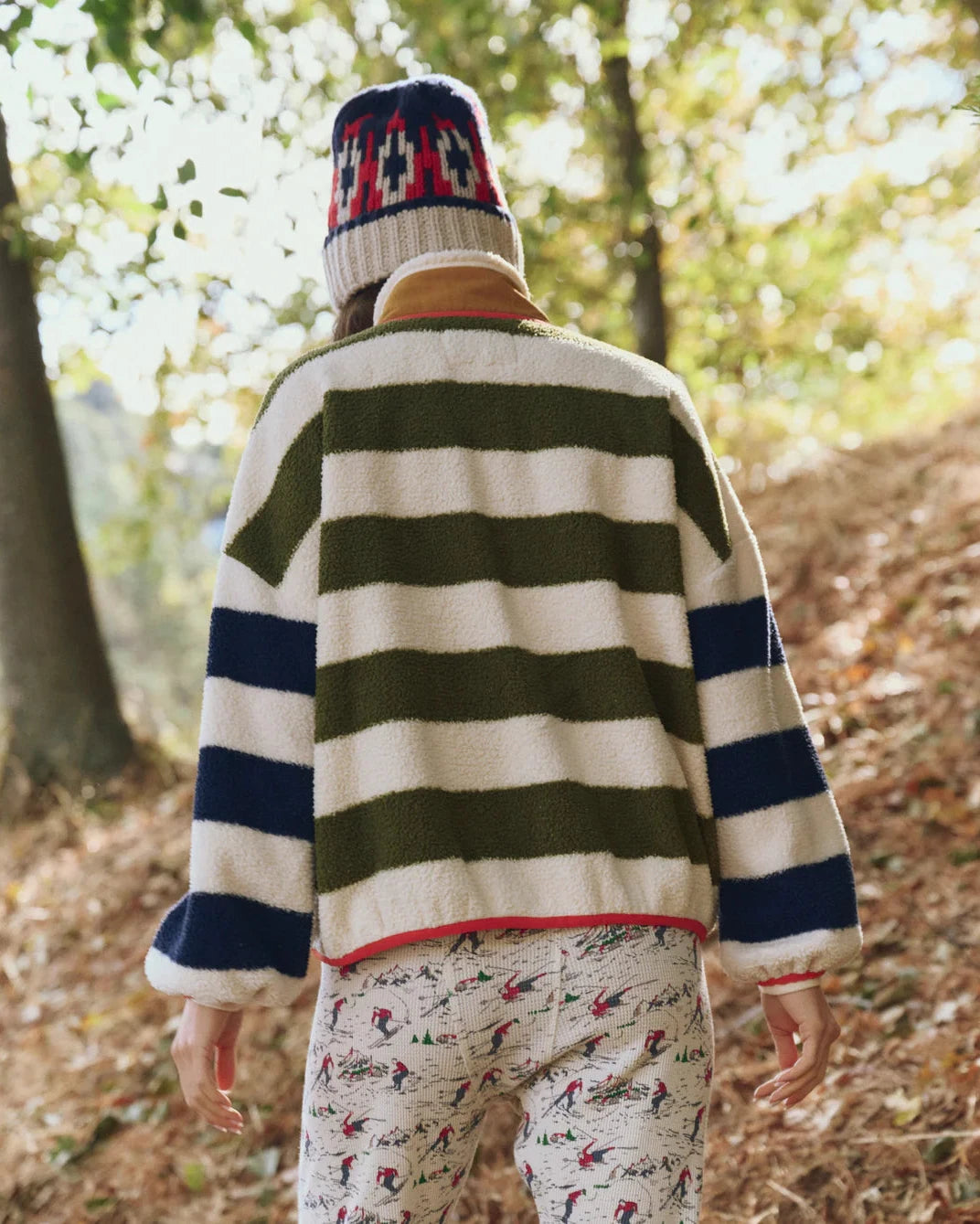 Person wearing a striped sweater and beanie in a forest setting