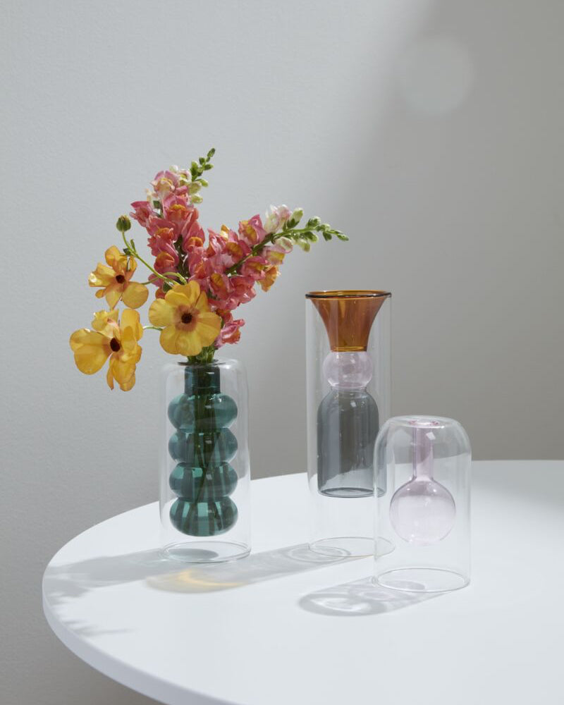Vase with flowers on a white table against a plain wall