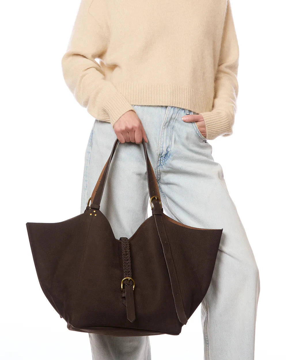 Person holding a brown leather handbag against a white background