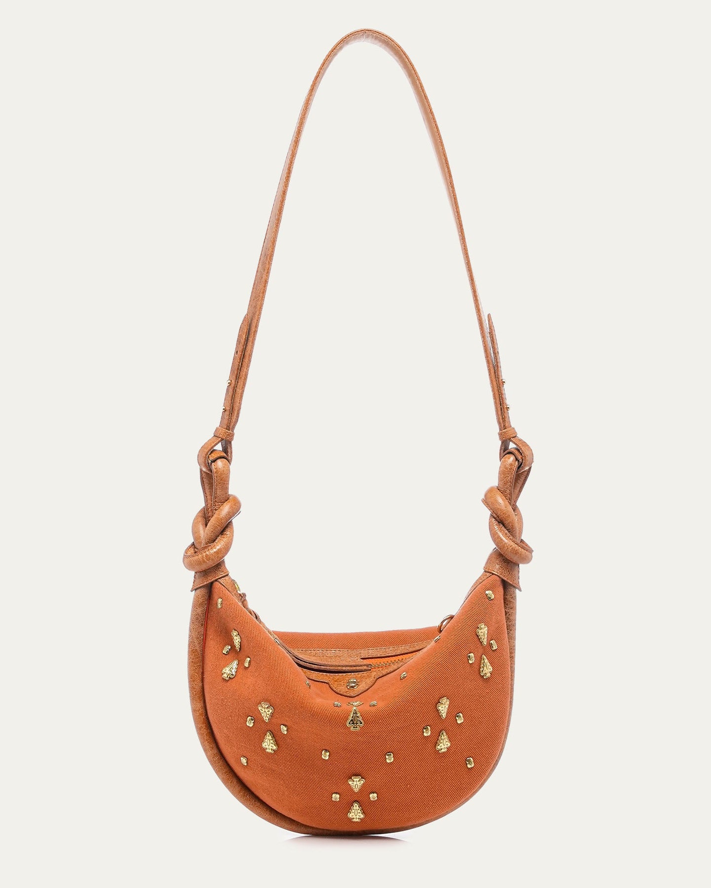 Brown leather handbag with gold studs on a light beige background