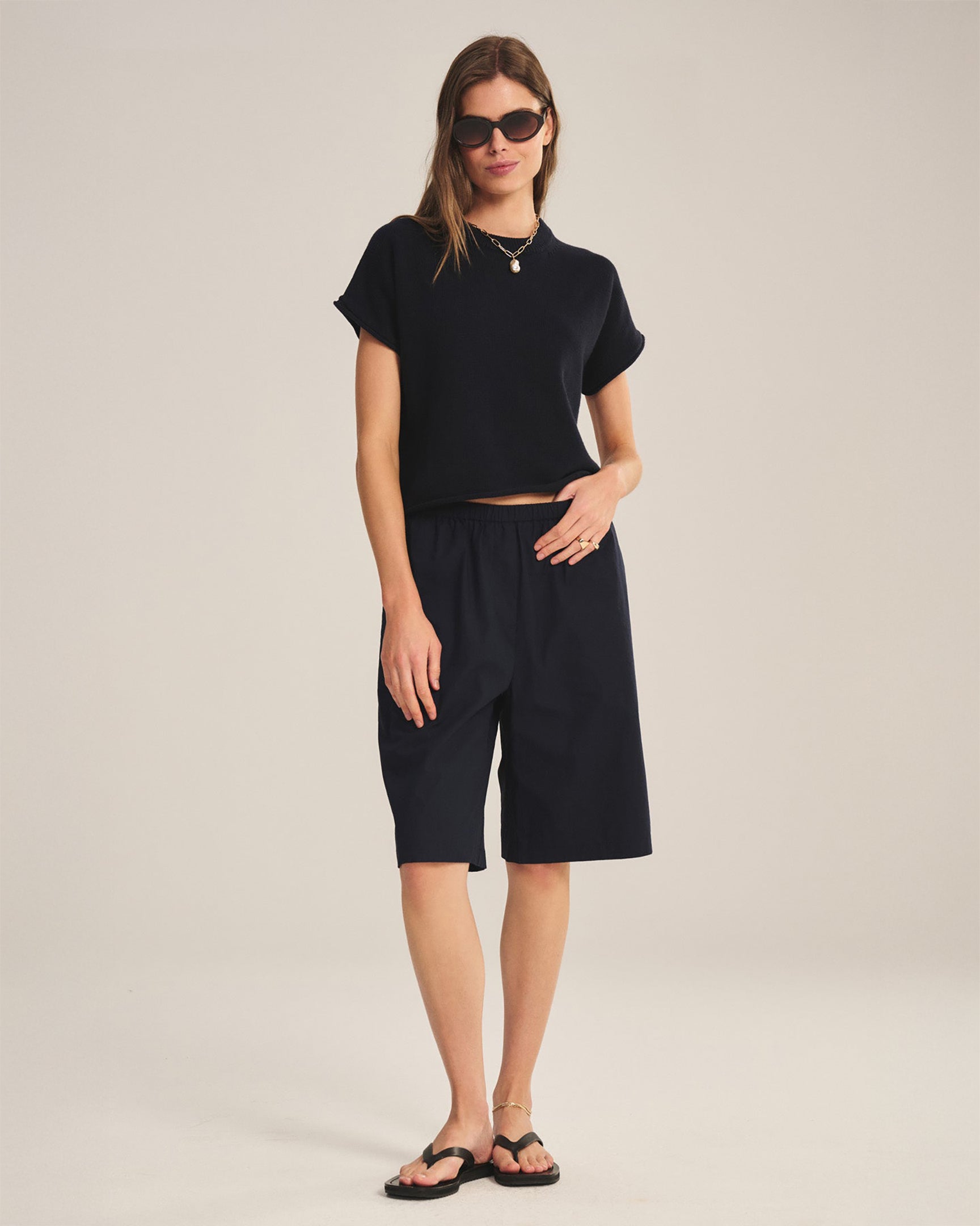 Woman wearing a black outfit with shorts on a plain background