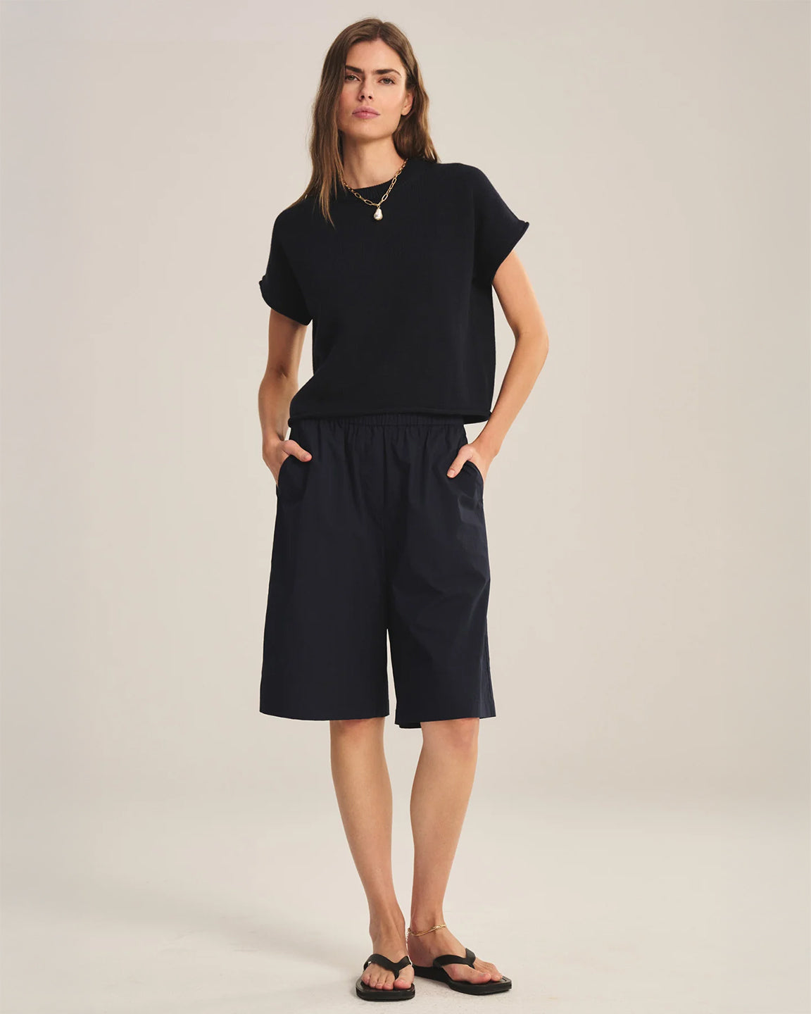 Woman wearing a black outfit with a top and shorts on a plain background
