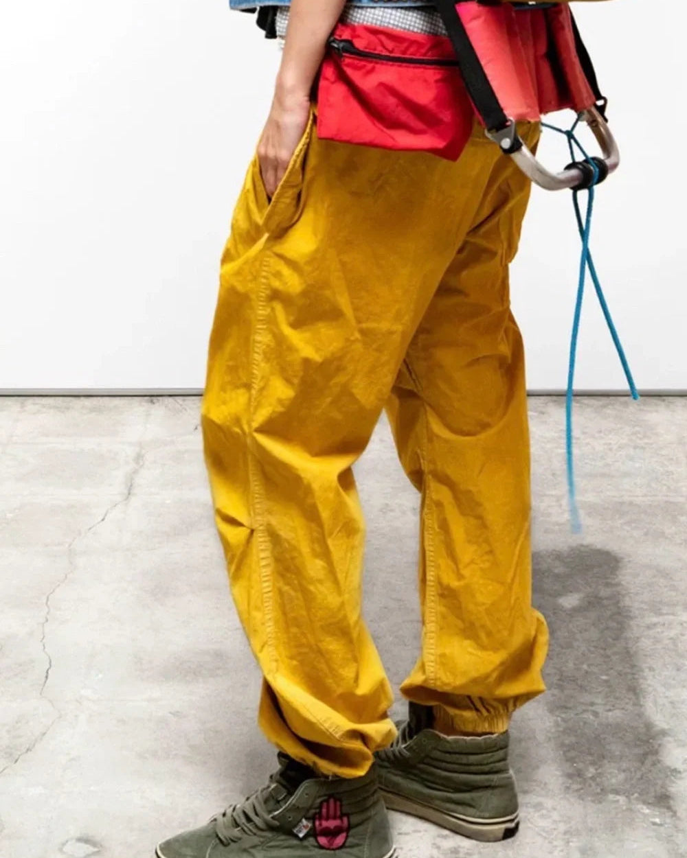 Person wearing yellow pants and green shoes on a light gray floor.