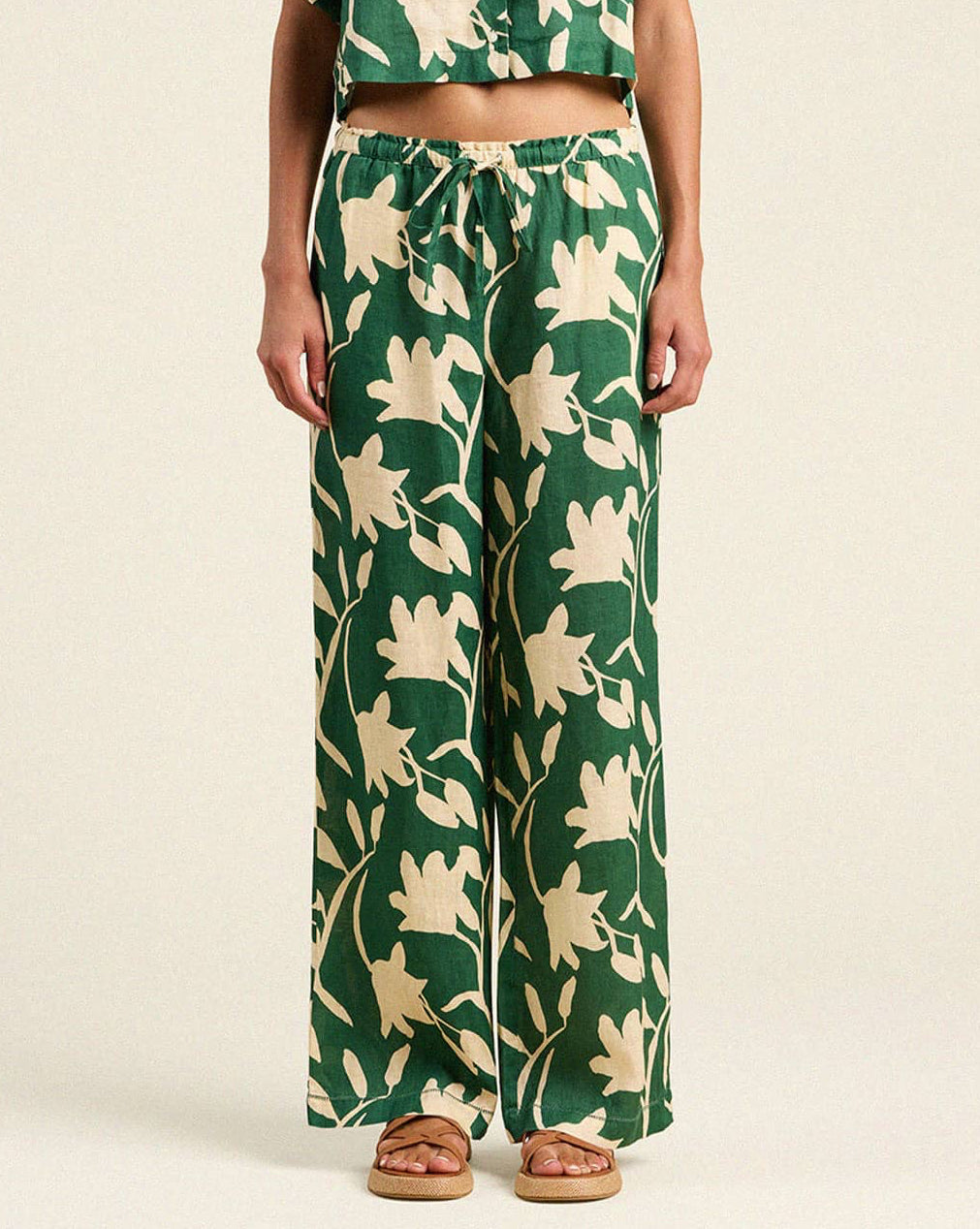 Person wearing a green and beige floral patterned outfit on a plain background