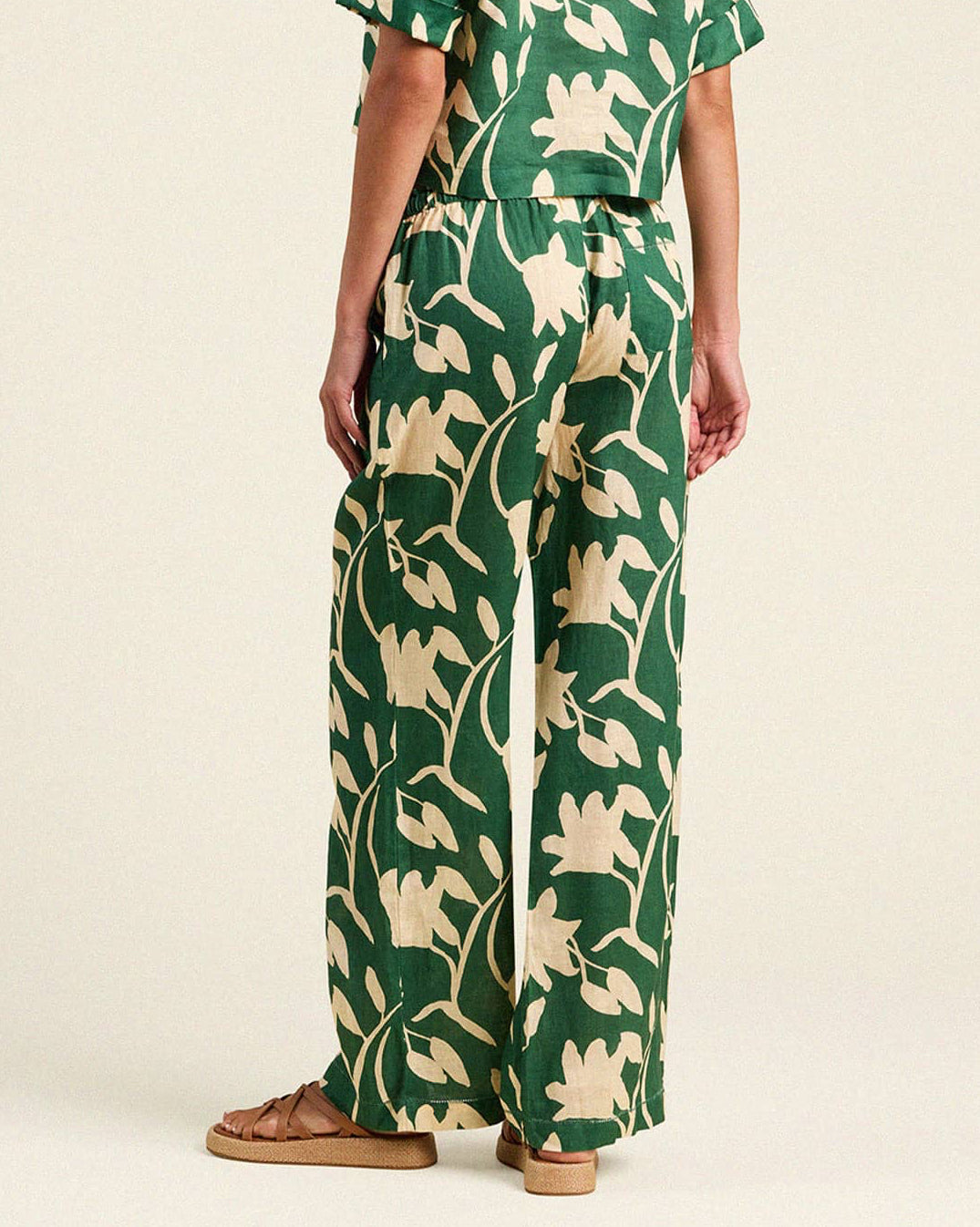 Person wearing a green and beige floral patterned dress on a white background