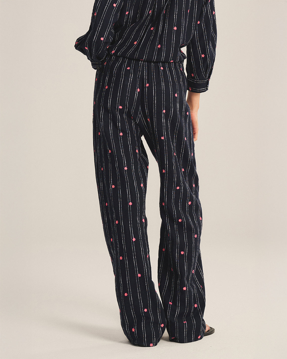 Black pajama set with white stripes and pink dots on a beige background
