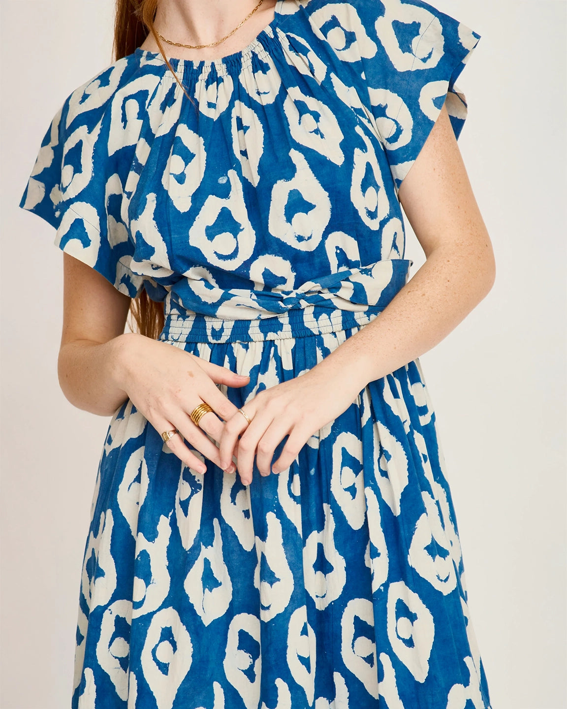Blue dress with white pattern worn by a person on a plain background