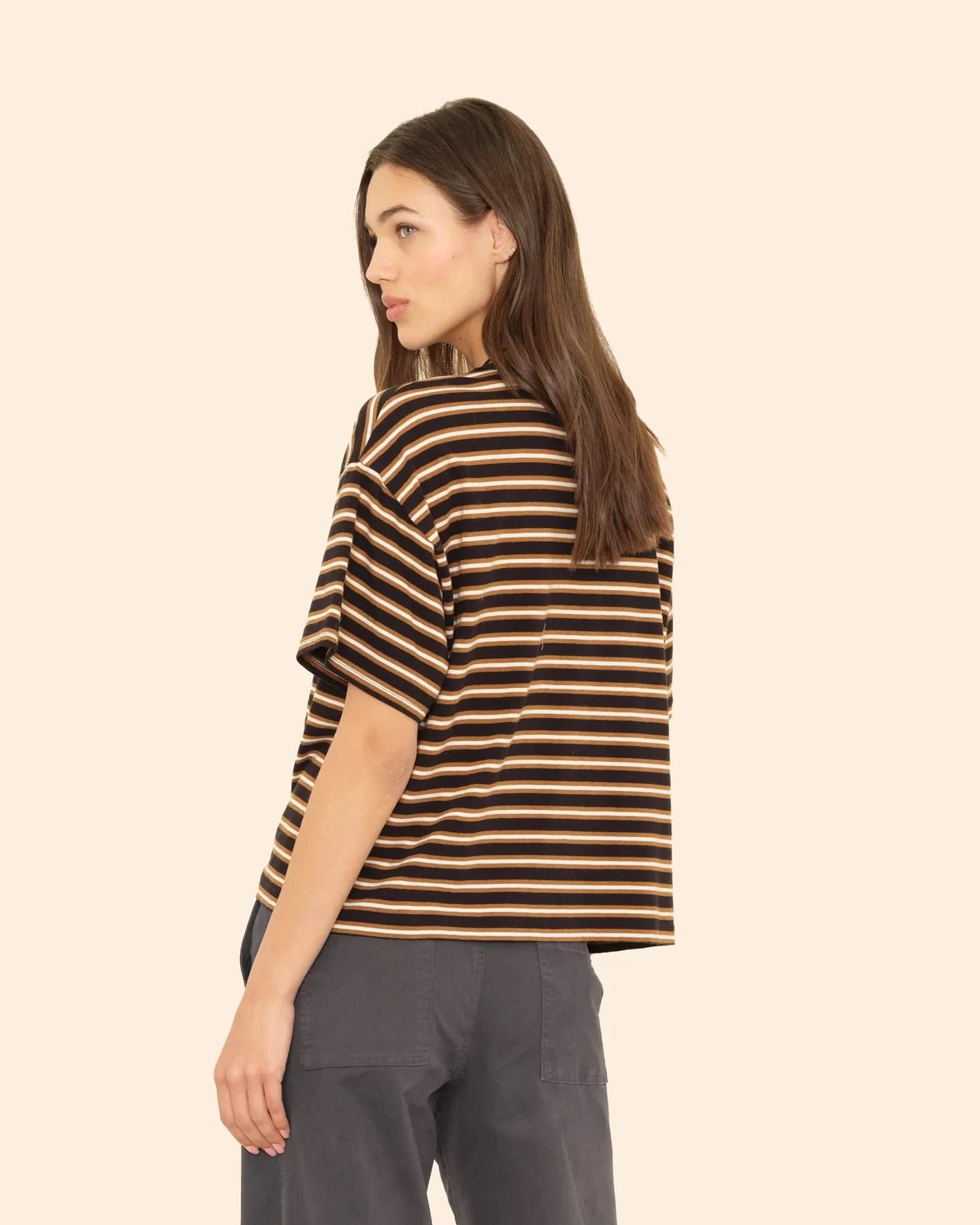 Woman wearing a black and beige striped shirt on a beige background