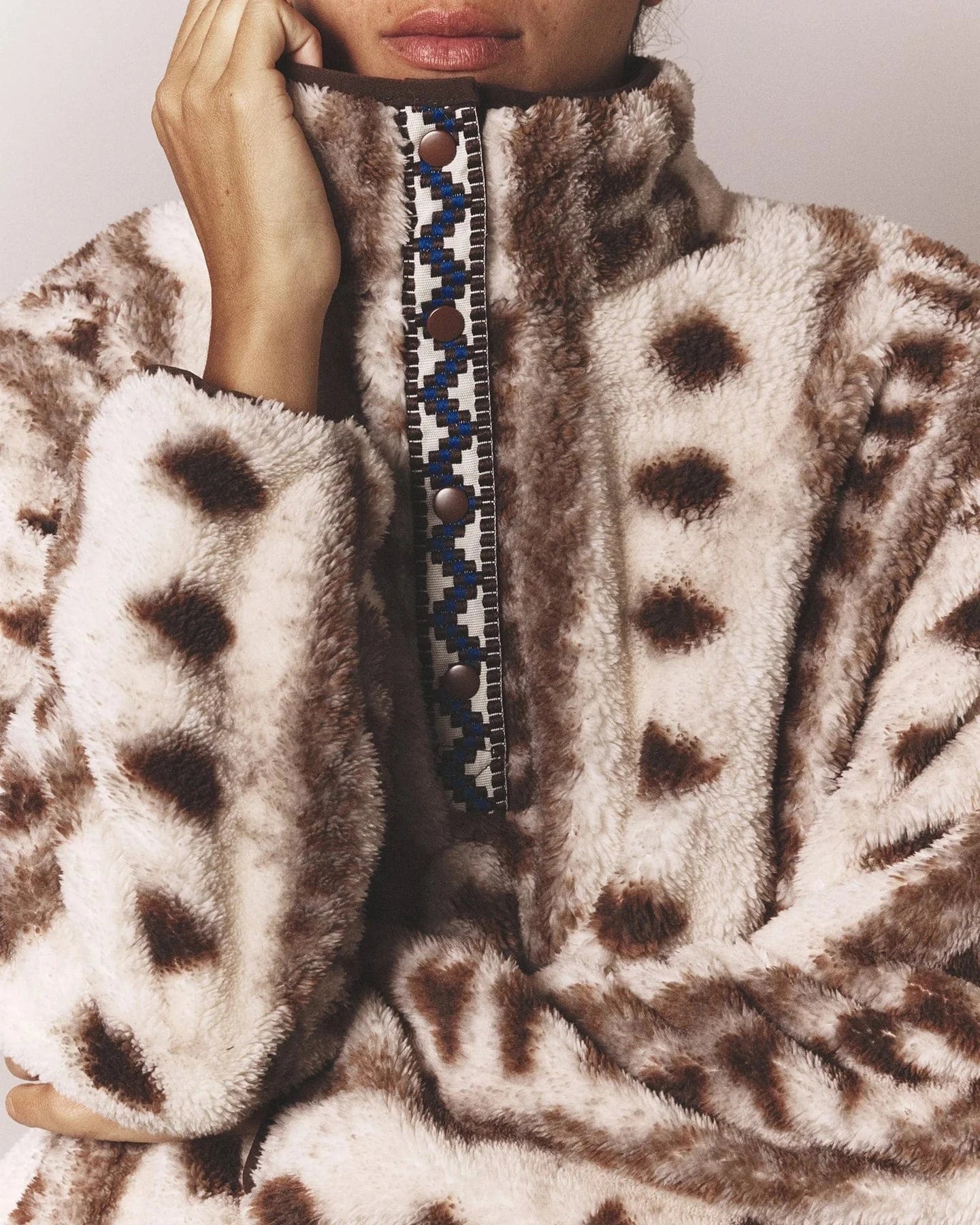 Close-up of a person wearing a patterned fur coat with a geometric design on the collar.