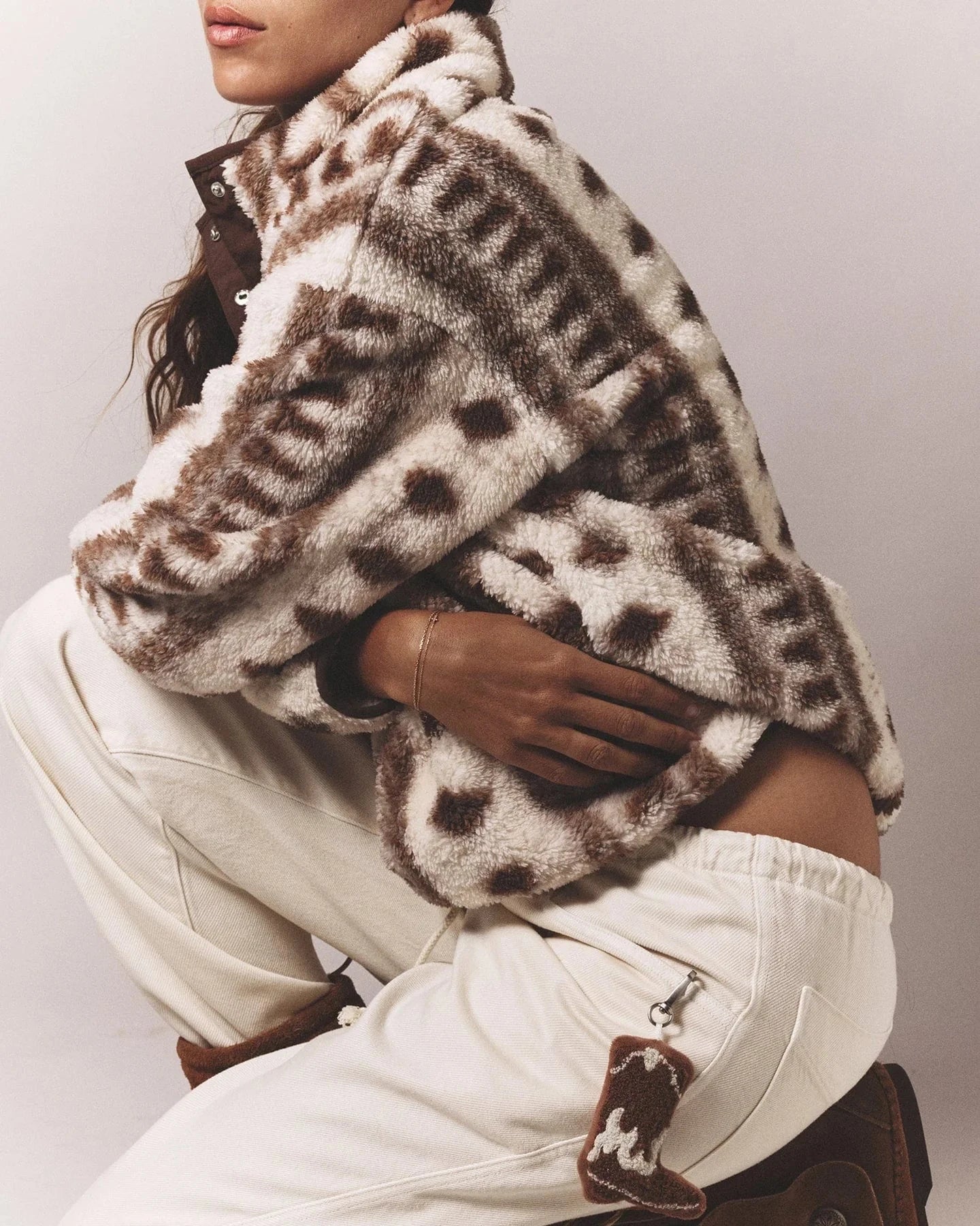 Person wearing a patterned jacket and white pants against a neutral background